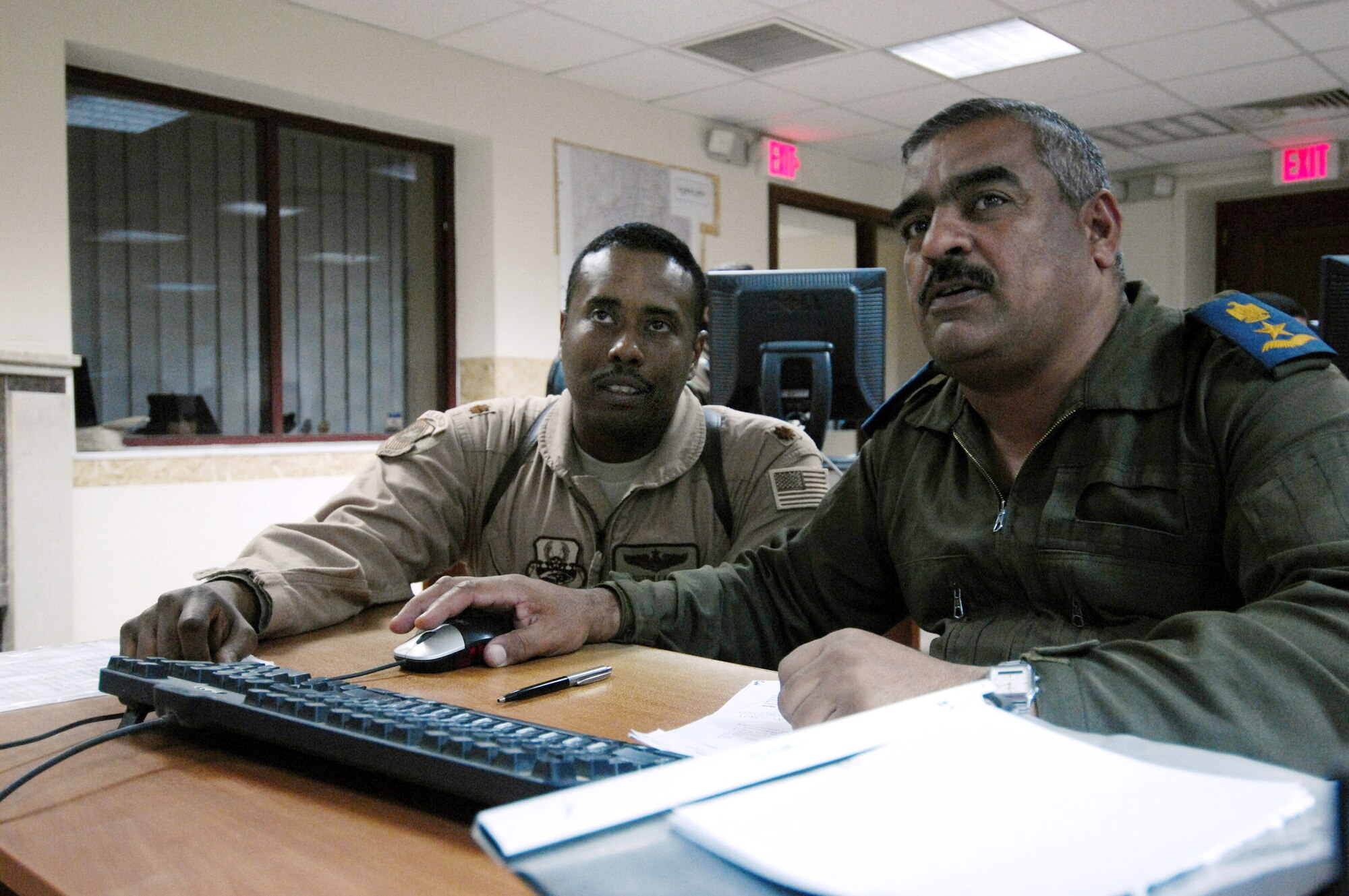 Maj. Kingston Lampley advises an Iraqi air operations center officer about maintaining an air tasking order at the Iraqi Air Operations Center at Camp Victory, Iraq, May 28. Major Lampley is a military transition team member, advising Iraqi officers concerning the day-to-day operations in their air operations center. The Iraqi AOC is run completely by Iraqi military officers and advised by Air Force military transition team officers. The AOC MTT is responsible for teaching and preparing the Iraqi military to take over AOC operations independent from the U.S. military. (U.S. Air Force photo/Staff Sgt. Christina M. Styer)
