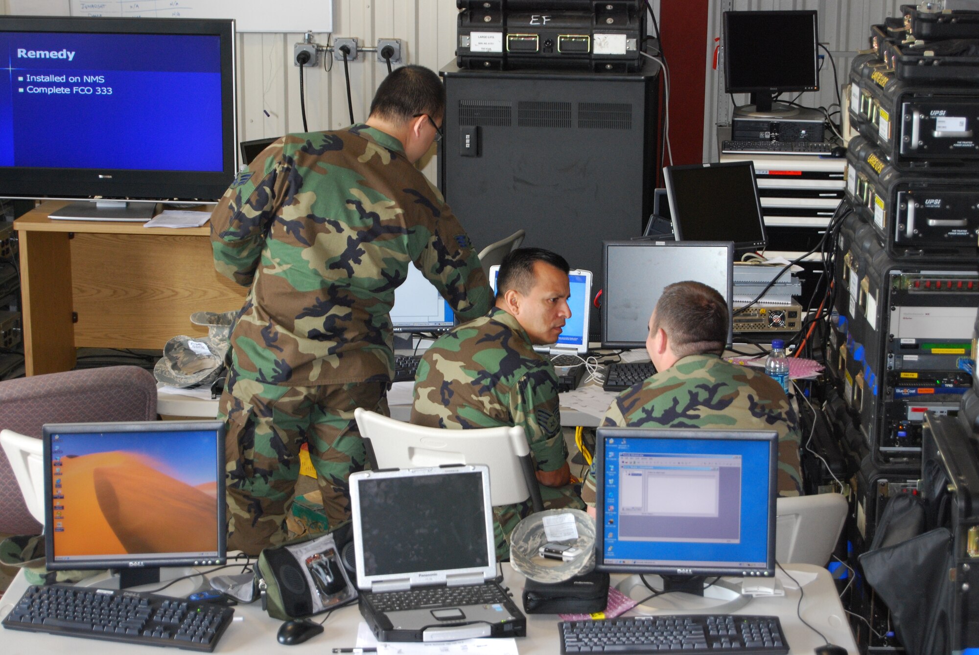 Staff Sgt. Edgar Bonilla (center) consults with Staff Sgt. Sean Walsh (right) while configuring the Remedy Trouble Ticket Tracking software on the Theater Deployable Communications Network Control Center - Deployable Network Management Server. Sergeants Bonilla and Walsh are computer operators with the 944th Communications Flight. (U.S. Air Force photo/Chief Master Sgt. Steve Plante)