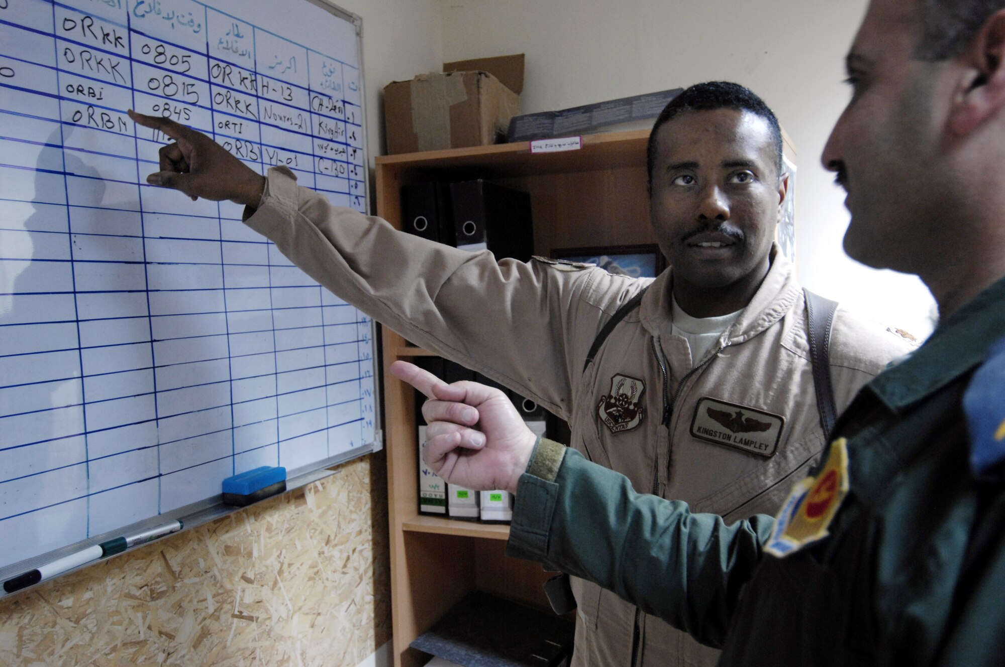 U.S. Air Force Maj. Kingston Lampley advises an Iraqi Air Operations Center officer about proper flight schedules at the Iraqi Air Operations Center at Camp Victory, Iraq on May 28, 2008. Maj. Lampley is a Military Transition Team member advising Iraqi officers concerning the day to day operations in their Air Operations Center. The Iraqi AOC is run completely by Iraqi military officers and advised by U.S. Air Force Military Transition Team (MTT) officers. The AOC MTT is responsible for teaching and preparing the Iraqi military to take over AOC operations independent from the U.S. military. (U.S. Air Force photo by: Staff Sgt. Christina M. Styer)