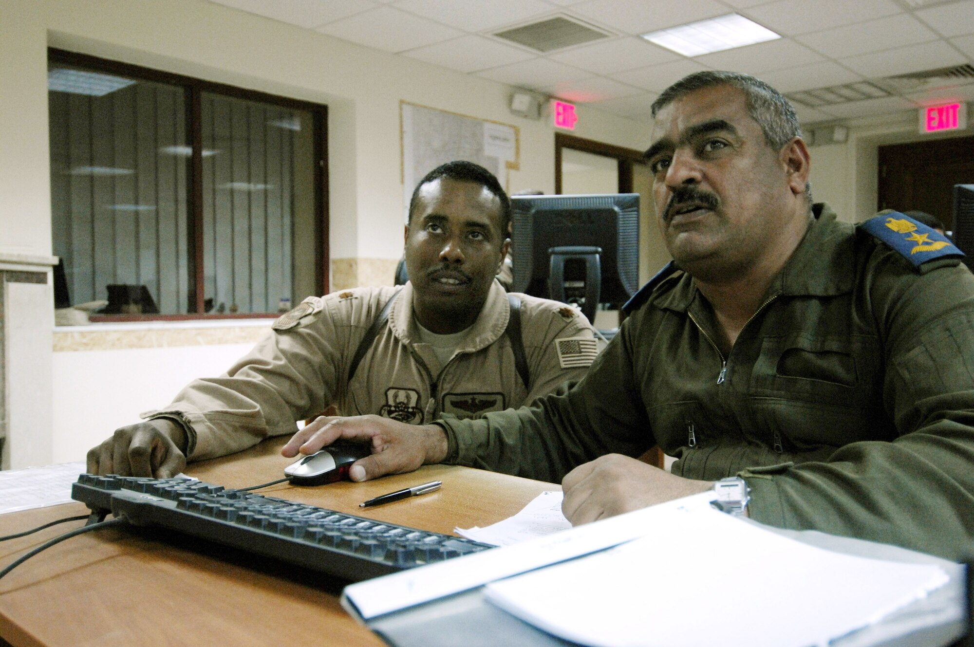 U.S. Air Force Maj. Kingston Lampley advises an Iraqi Air Operations Center officer about maintaining an Air Tasking Order at the Iraqi Air Operations Center at Camp Victory, Iraq on May 28, 2008. Maj. Lampley is a Military Transition Team member advising Iraqi officers concerning the day to day operations in their Air Operations Center. The Iraqi AOC is run completely by Iraqi military officers and advised by U.S. Air Force Military Transition Team (MTT) officers. The AOC MTT is responsible for teaching and preparing the Iraqi military to take over AOC operations independent from the U.S. military.  (U.S. Air Force photo by: Staff Sgt. Christina M. Styer)

