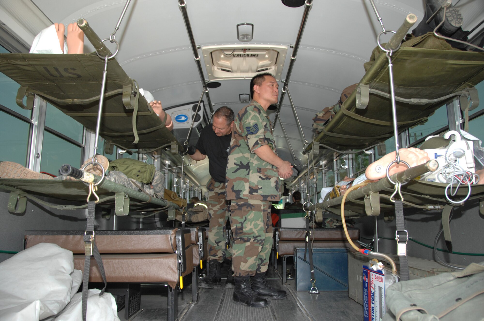 TRAVIS AIR FORCE BASE, Calif. -- All aboard: (left to right) Technical Sgt. Raymond Greth and Technical Sgt. Rowland Suico, both medical logistics technicians with the 349th Aeromedical Staging Squadron, Travis Air Force Base, Calif., participate in a field training exercise at Osan Air Base, Korea. They are comforting simulated patients on the bus and making final checks to insure the patients are secure for the next leg of their journey—an aircraft headed for medical facilities capable of treating their injuries. The members of the 349th ASTS were in Osan to perform their annual tour by assisting active duty Air Force personnel in setting up a 100-bed Contingency Aeromedical Staging Facility in the field, inventoring all parts and then repacking. (U.S. Air Force photo by Master Sgt. Wendy Weidenhamer)
