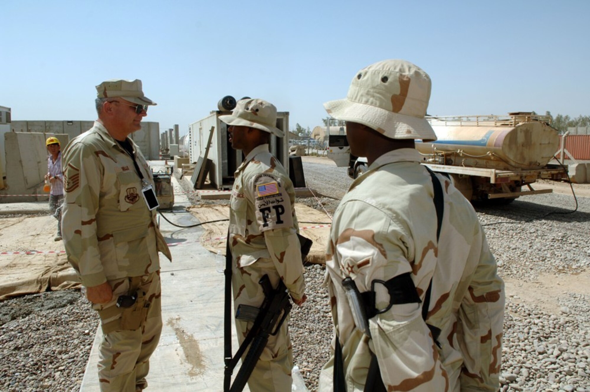 Master Sgt. Chris Selle, 332nd Air Expeditionary Wing superintendent in charge of force protection, speaks with two of his Airmen as they escort third-country nationals at Balad AB, Iraq. Sergeant Selle is an engine propulsion craftsman from the 315th Aircraft Maintenance Squadron who volunteered for this duty, which he extended twice making it a year long.  