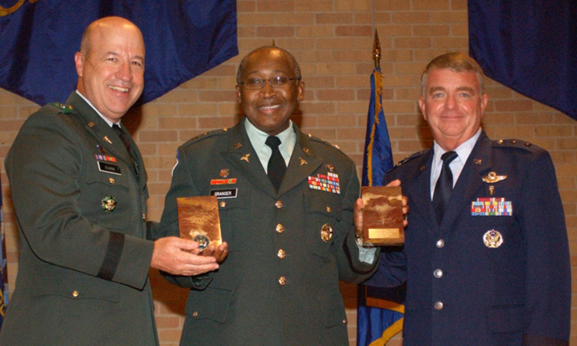 Brooke Army Medical Center Commander Brig. Gen. James Gilman (left) and 59th Medical Wing Commander Maj. Gen. Tom Travis (right) present gifts to Maj. Gen. (Dr.) Elder Granger (center), at the San Antonio Uniformed Services Health Education Consortium awards and graduation ceremony June 6 in the University of Texas Health Science Center at San Antonio auditorium. General Granger, deputy director and program executive officer of the TRICARE Management Activity, Office of the Assistant Secretary of Defense (Health Affairs), was the keynote speaker at the event which honored 241 physicians and allied health care providers. (U.S. Air Force Photo/Alan Boedeker)