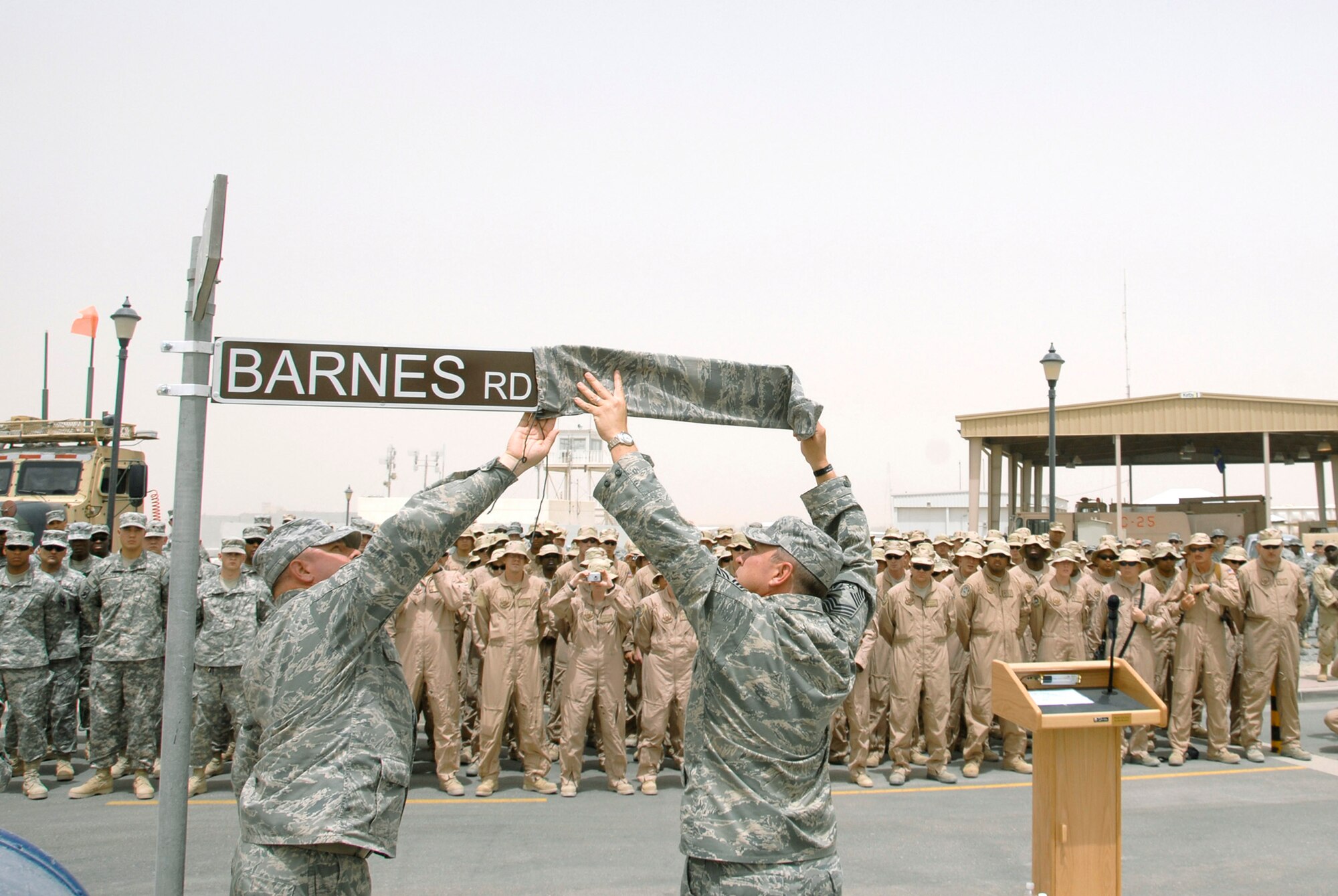 Chief Master Sergeant Carl Hunsinger (left) and Chief Master Sgt. Richard Bunce (center), unveil the new street sign during a dedication ceremony June 10 in Southwest Asia. The street dedication ceremony is a tribute to Airman 1st Class Eric Barnes. Airman Barnes, 20, of Lorain, Ohio, died June 10, 2007 as a result of an improved explosive device attack on an Air Force convoy about 100 miles south of Baghdad, Iraq. He was deployed from the 90th Logistics Readiness Squadron at F.E. Warren Air Force Base, Wyo. Chief Hunsinger is the 386th Air Expeditionary Wing command chief and Chief Bunce is the 100th Logistics Readiness Squadron chief enlisted manager, who Airman Barnes worked for at the time of his death in 2007. (U.S. Air Force photo/Staff Sgt. Patrick Dixon) 