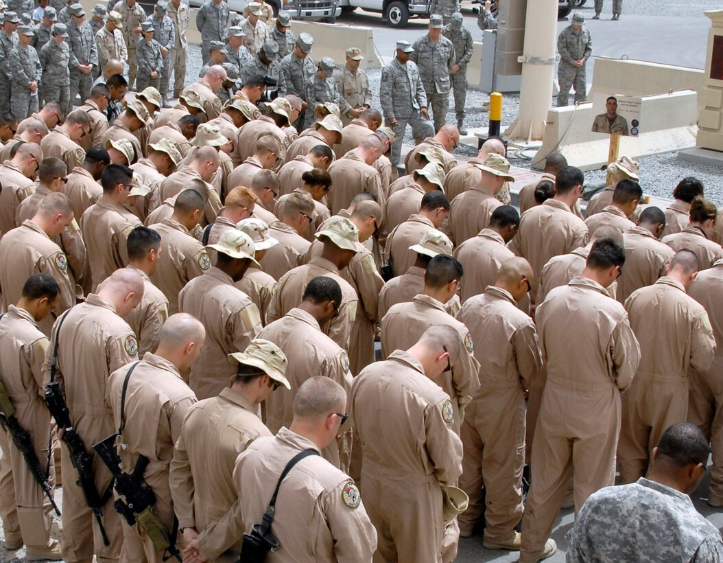 Airmen from the 586th Expeditionary Logistics Readiness Squadron, 70th and 424th Medium Truck detachments and Soldiers from the Army's 1st Theater Support Command, 640th Sustainment Brigade, 1144th Transportation Battalion, along with other Airmen from the 386th Air Expeditionary Wing, take a moment to pray for the family of a fellow Airman who made the ultimate sacrifices during a street dedication ceremony June 10 in Southwest Asia. The ceremony is a tribute to Airman 1st Class Eric Barnes who died June 10, 2007, as a result of an improved explosive device attack on an Air Force convoy about 100 miles south of Baghdad, Iraq. (U.S. Air Force photo/Tech. Sgt. Michael O'Connor) 