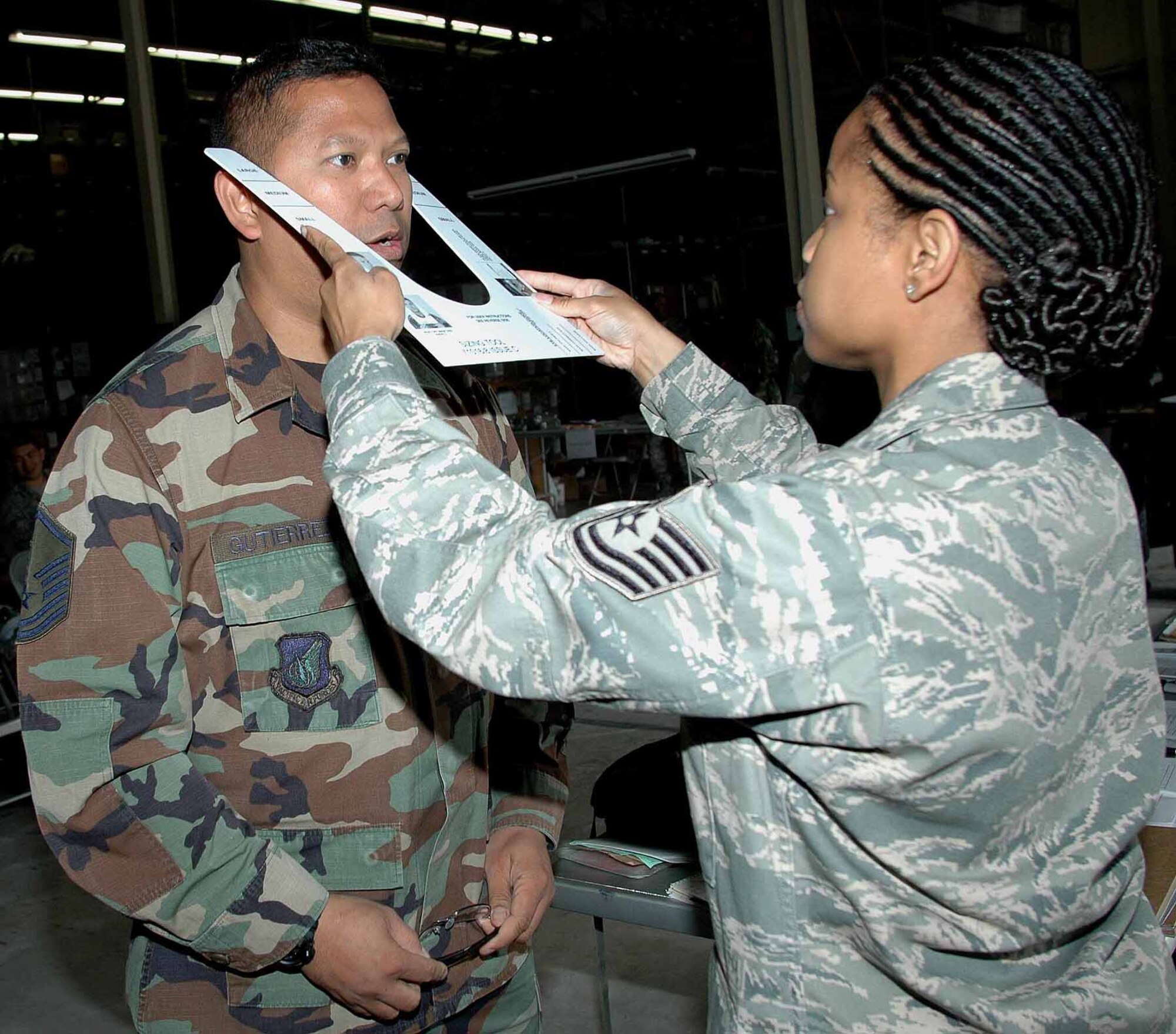 OSAN AIR BASE, Republic of Korea -- Tech. Sgt. Kochitia Kimbrough, 51st Logistics Readiness Squadron, measures Master Sgt. Roberto Gutierrez, 51st Medical Operations Squadron for his new M-50 protective mask June 9. (U.S. Air Force photo/Staff Sgt. Candy Knight)