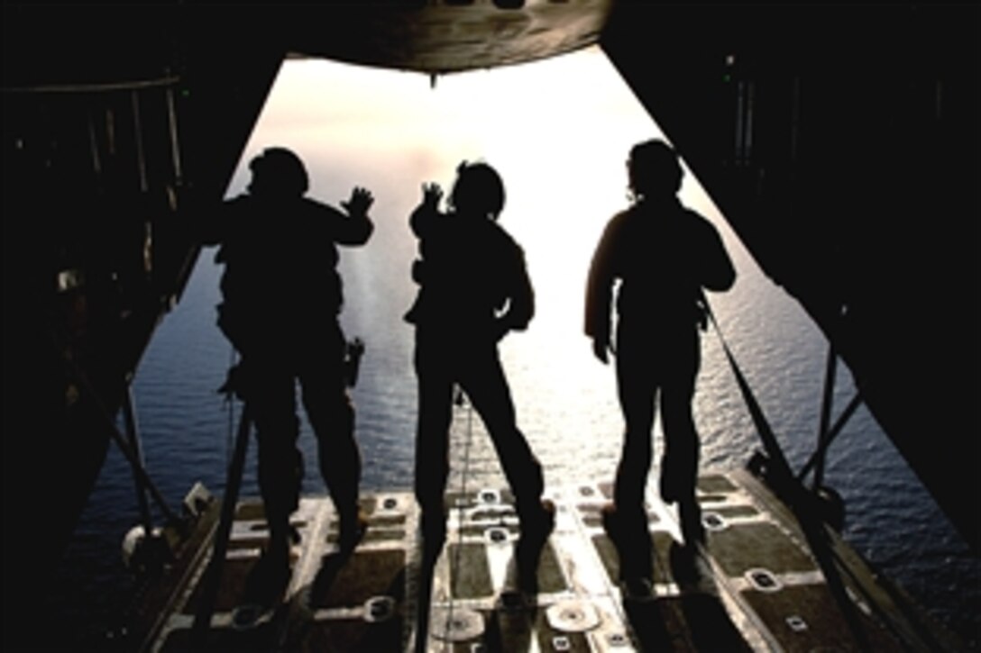 U.S. Air Force Tech. Sgt. James Floyd, Airman 1st Class Nicholas Greer and Senior Airman Martin Smith, all loadmasters, watch a smoke grenades from the back ramp of an aircraft during a mission off the coast of Djibouti, June 3, 2008.