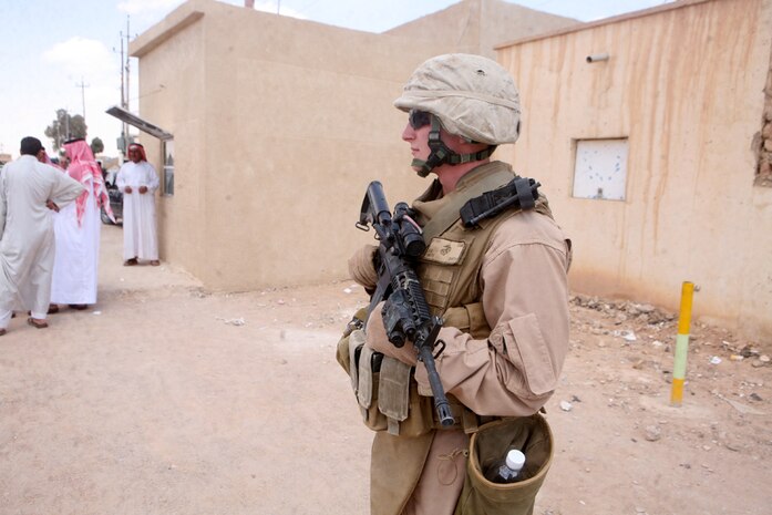 Cpl. Daniel M. Smith, 21, a squad leader with Security Platoon, Headquarters and Service Company, 2nd Light Armored Reconnaissance Battalion, Regimental Combat Team 5, provides security during a patrol through Rutbah, Iraq, June 11. "Our mission is to provide security for the Coaliton leaders while interacting with Iraqi leaders of Rutbah," said Smith, from Sacramento, Calif. "We're here to help build a better infrastructure in Iraq."::r::::n::