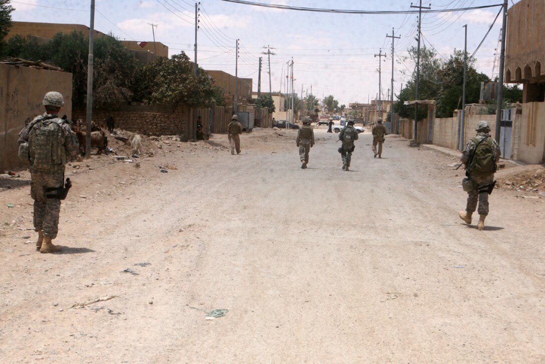 Providing security during a patrol, Lance Cpl. Sergio A. Flores-Reyes, 20, a scout from San Juan, Texas, with Security Platoon, Headquarters and Service Company, 2nd Light Armored Reconnaissance Battalion, Regimental Combat Team 5, watches the streets of Rutbah, Iraq, June 11. The platoon visits the city weekly to converse with the people and to escort key personnel.