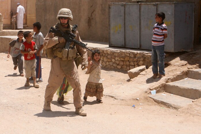 While patrolling through Rutbah, Iraq, Cpl. Daniel M. Smith, a squad leader with Security Platoon, Headquarters and Service Company, 2nd Light Armored Reconnaissance Battalion, Regimental Combat Team 5, is followed by a group of local children June 11. The platoon visits the town weekly to converse with the residents and conduct city counsel meetings with the leaders.::r::::n::