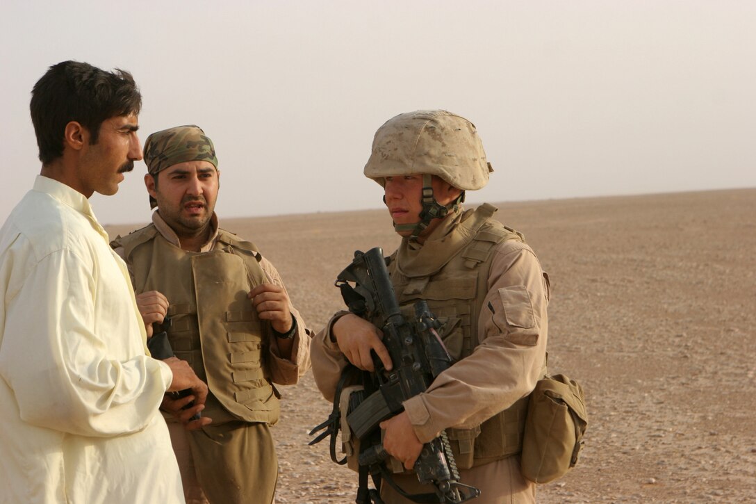 (June 11, 2008) - Corporal Aaron Payne, assistant patrol leader, 2nd platoon, Bravo Company, Marine Wing Support Squadron 274, 3rd Marine Aircraft Wing (Forward), speaks to an Iraqi national with the help of his interpreter. When Payne interacts with Iraqis he uses the opportunity to learn about their culture and teach them a little about Americans to improve the working relationship with locals and Coalition forces.