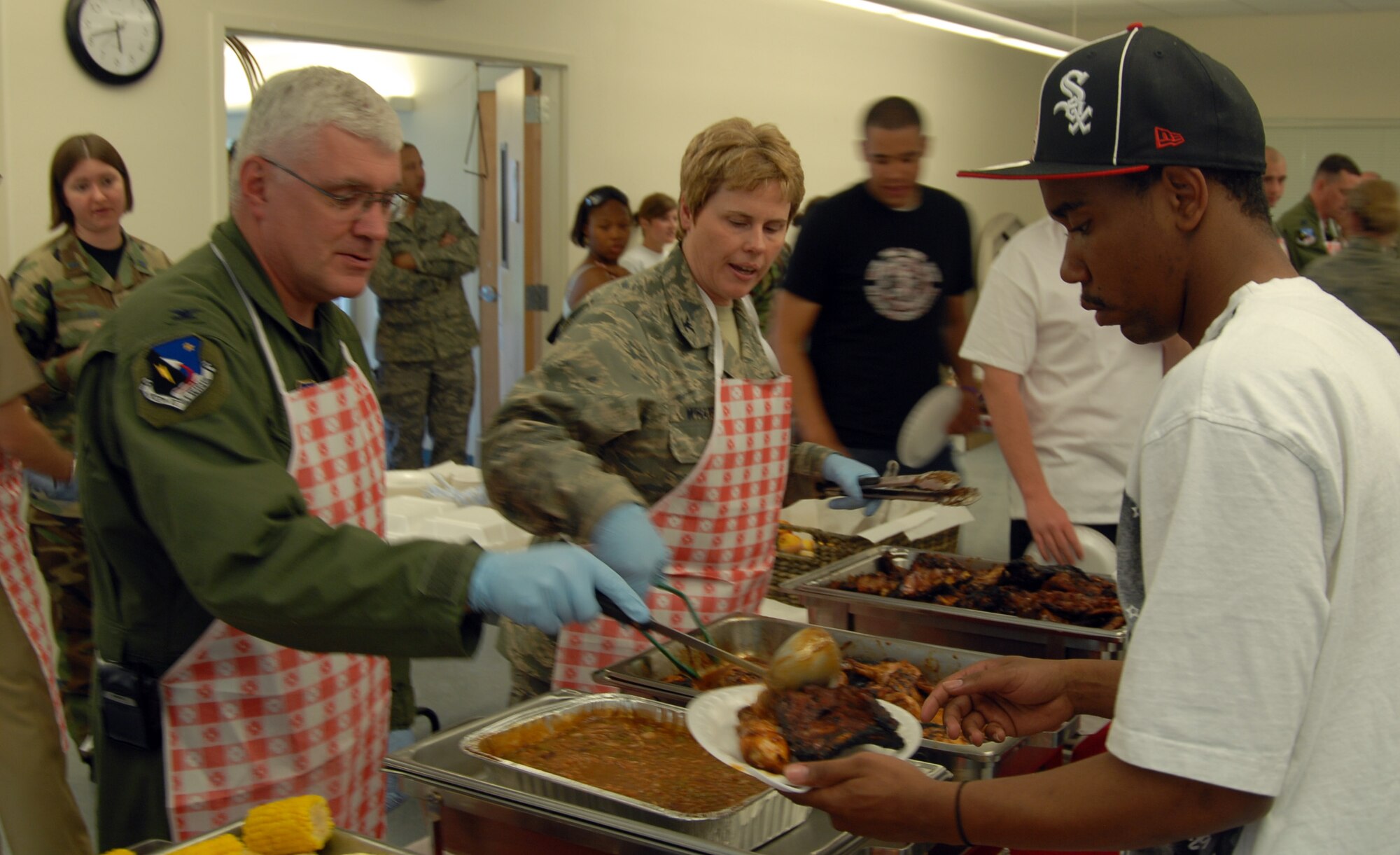 Col. Daniel Morin (left),  412th Test Wing vice commander, and Col. Nancy Wharton (center), 95th Air Base Wing vice commander, serve food to Airman Cecil White, 95th Security Forces Squadron installation patrolman, during a dorm dwellers dinner at the Chapel 1 Annex here June 11. (Air Force photo by Airman 1st Class William O'Brien)