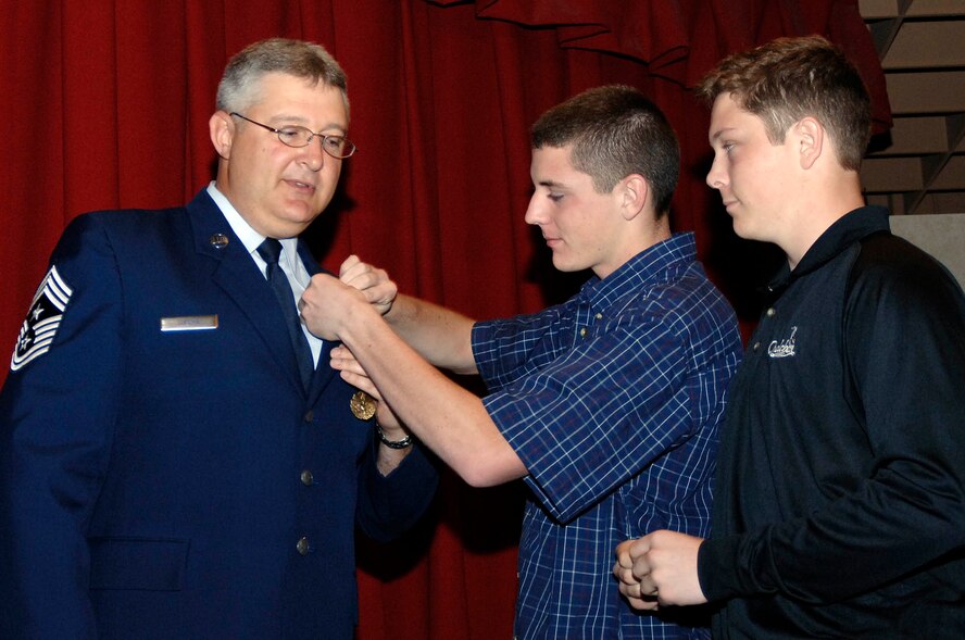 FAIRCHILD AIR FORCE BASE, Wash. – Chief Master Sgt. Paul Sikora, 92nd Air Refueling Wing command chief, receives his retirement pin from son Ryan, 16 (right), and Scott, 18. Spending more time with his family, specifically his son Ryan who still lives at home, was a “big reason behind my decision to retire,” said Chief Sikora. The chief has served the Air Force for 27 years and is now headed to Las Vegas, Nev. (U.S. Air Force photo / Staff Sgt. JT May III)