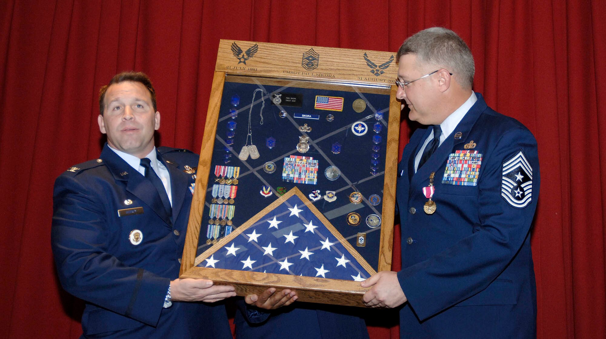 FAIRCHILD AIR FORCE BASE, Wash. – Col. Thomas Sharpy (left), 92nd Air Refueling Wing commander, displays Chief Master Sgt. Paul Sikora’s shadow box at the chief’s retirement ceremony June 12 at Club Fairchild here. The chief has served as the 92nd ARW command chief since May 2007, during which time he has “been an incredible leader. He us a warrior, a mentor, an Airman and someone who cares deeply about his people,” said Colonel Sharpy. (U.S. Air Force photo / Staff Sgt. JT May III)