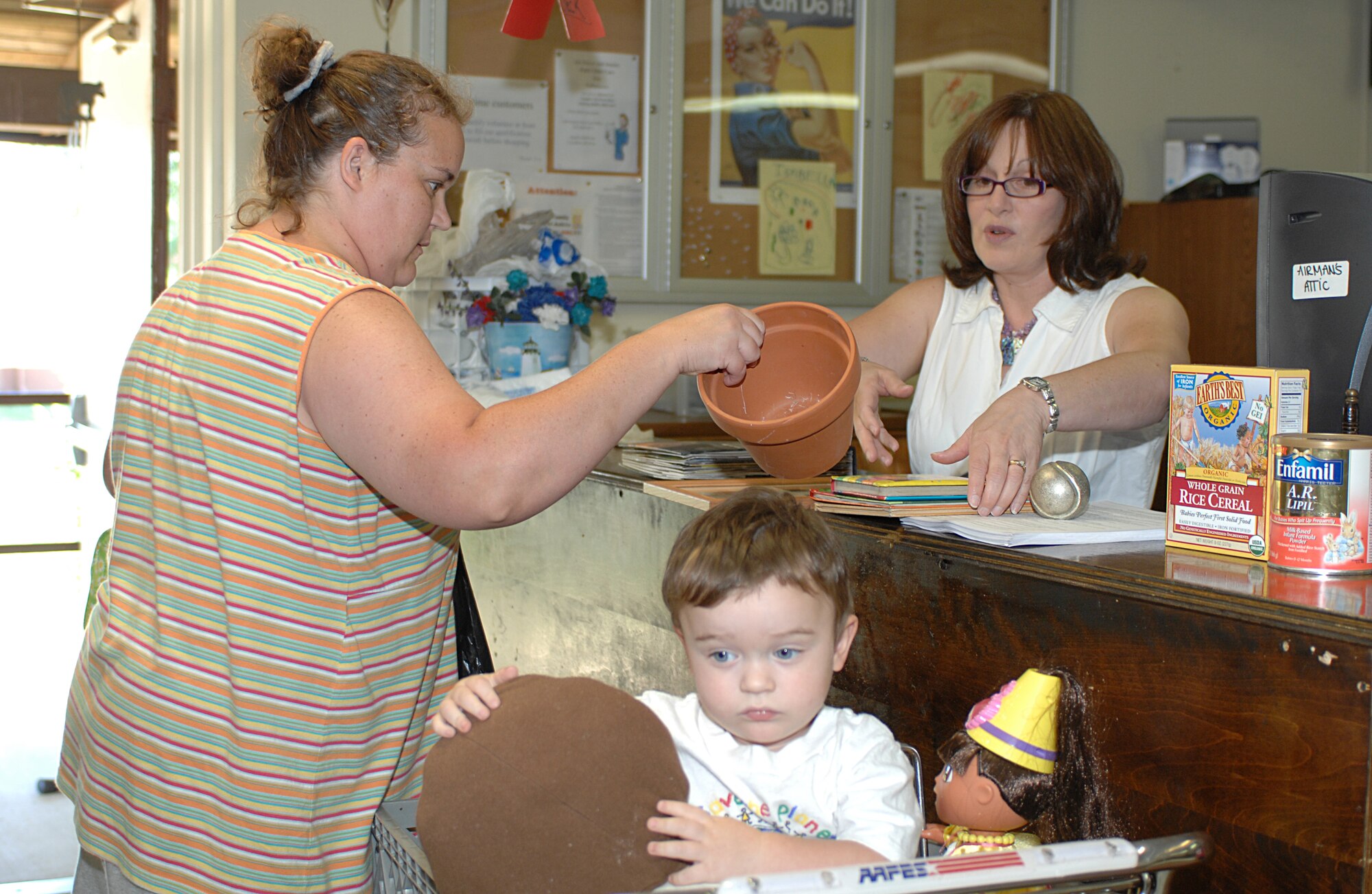 LANGLEY AIR FORCE BASE, Va. -- Ms. Brenda Fisher (right) checks out a flowerpot, books and other free items for Mrs. Joan Kirkpatrick, wife of Staff Sgt. Will Kirkpatrick, 94th Aircraft Maintenance Squadron crew chief, and her son, Quentin, at the Airman’s Attic June 12. Brenda has volunteered at the Airman’s Attic for more than two years. (U.S. Air Force photo/TSgt April Wickes) 