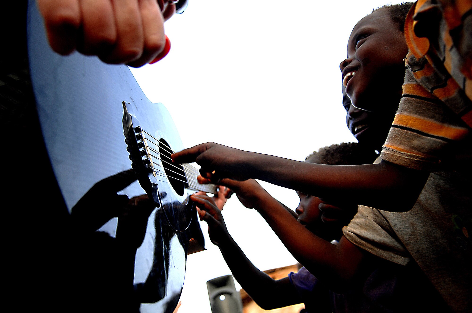 Djiboutian children explore Senior Master Sgt. Jimmy Weber's guitar during a performance May 22 by the Air Force Central command band, Falcon, in Negad, Djibouti.  The band is deployed in support of Combined Joint Task Force - Horn of Africa out of Camp Lemonier, Djibouti. (U.S. Air Force photo/Tech. Sgt. Jeremy T. Lock)