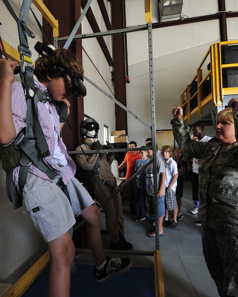 MOODY AIR FORCE BASE, Ga. -- Tech. Sgt. Sonya Couture, 23rd Operations Support Squadron aircrew flight equipment lead instructor, instructs a participant of the Lowndes County Sheriff's Office Drug Abuse Resistance Education camp on how to maneuver in the virtual reality parachute flight simulator as other participants watch his progress here June 11. The D.A.R.E. camp toured many units on Moody Air Force Base and learned about many interesting career fields. (U.S. Air Force photo by Senior Airman Elizabeth Rissmiller)