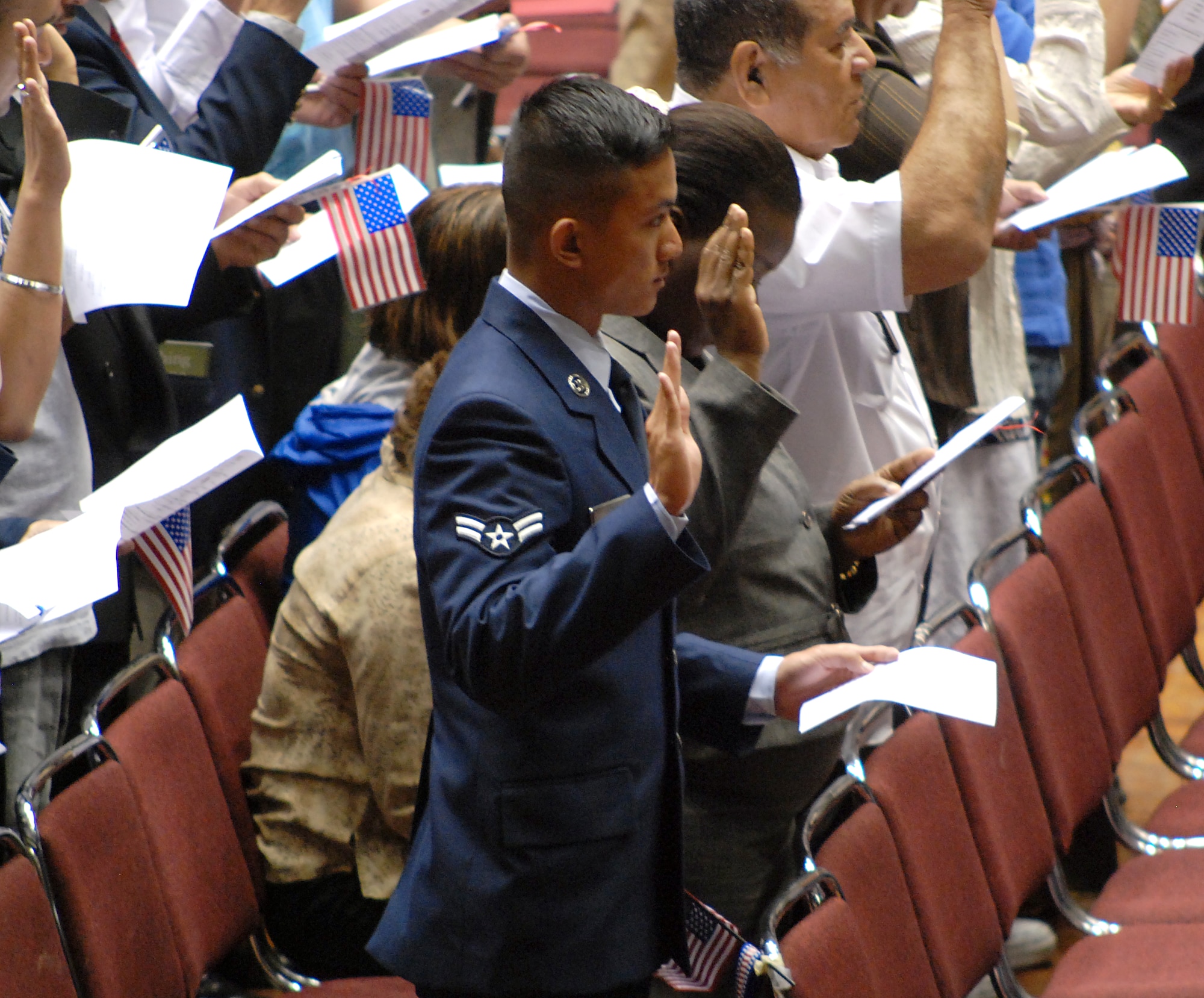 KANSAS CITY, Mo. -- Airman 1st Class Thanh Tran, 22nd Air Refueling Wing, raises his right hand to announce his allegiance to the United States in an oath of citizenship, at a naturalization ceremony, at the Municipal Auditorium, June 9.  Like his step-father, Tech. Sgt. Sam Pham, 93rd Intelligence Squadron, Lackland AFB, Texas, they both are active duty Air Force members who immigrated from Vietnam. (photo by Airman 1st  Class Jessica Lockoski)