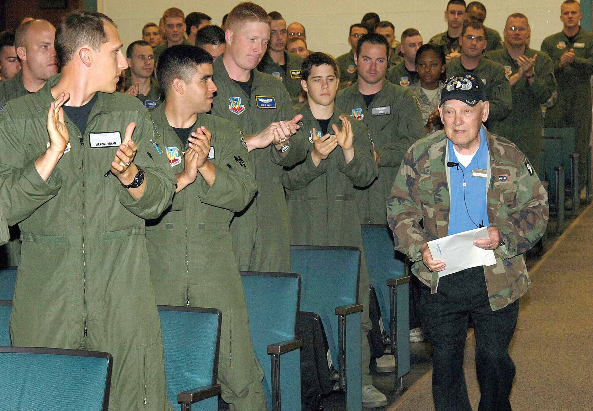 Airmen of the 552nd Air Control Wing quickly rise to offer a standing ovation as D-Day paratrooper Art Levine enters a wing auditorium June 6.  Mr. Levine, who jumped as a private first class but earned a battlefield commission within 30 days, shared World War II experiences on the 64th anniversary of the historical day.  (Air Force photo by Margo Wright)