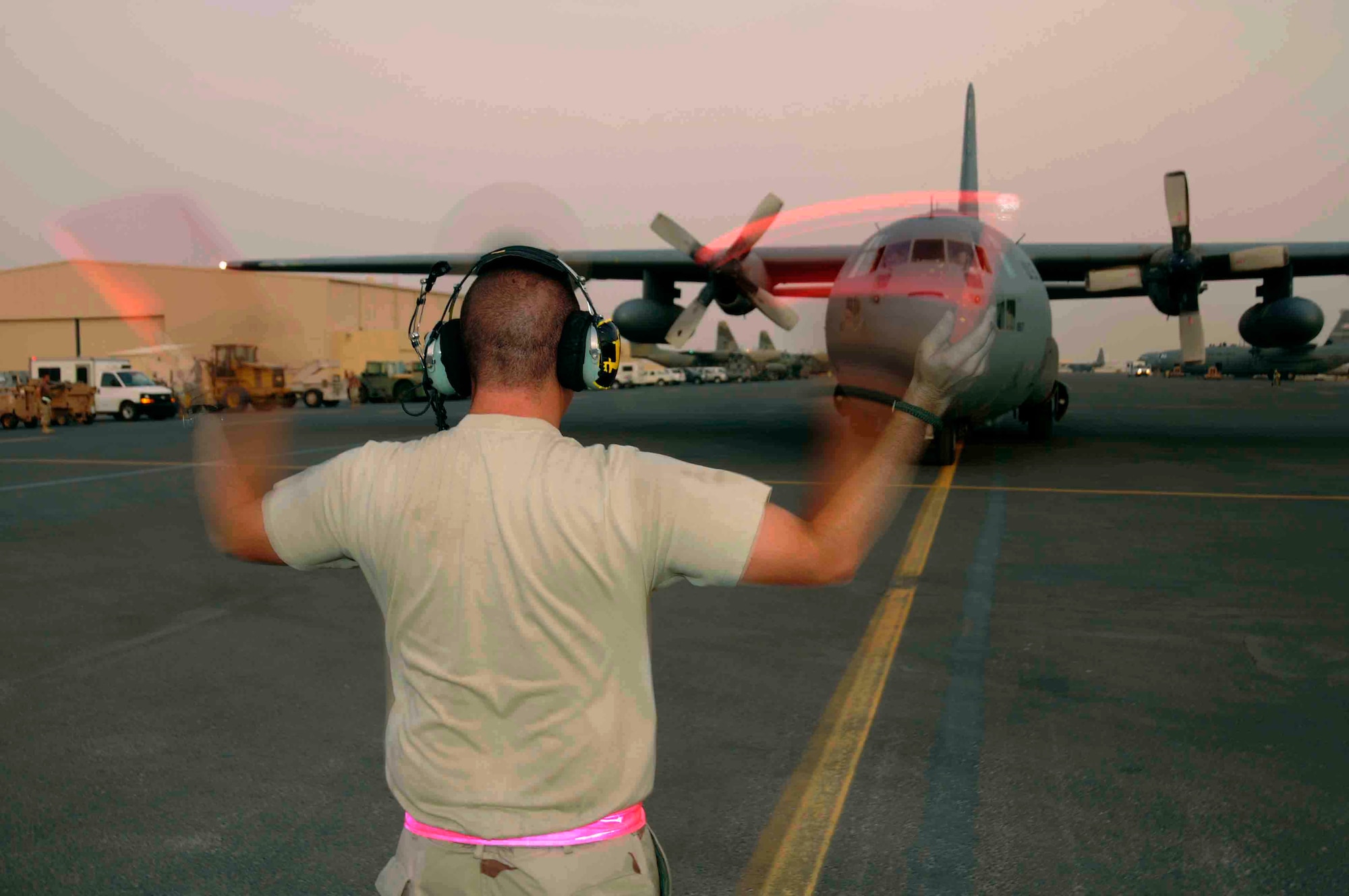 SOUTHWEST ASIA - Staff Sgt. Jonathan Osheim, 379th Expeditionary Airlift Maintenance Squadron, guides a C-130 aircraft into its final parking position on the ramp at a Southwest Asia air base after returning from a mission June 11.  Sergeant Osheim and his team will completely inspect, refuel, and prepare aircraft for its next mission. He is deployed from Pope Air Force Base, N.C. (U.S. Air Force photos/Tech. Sgt. Johnny Saldivar)