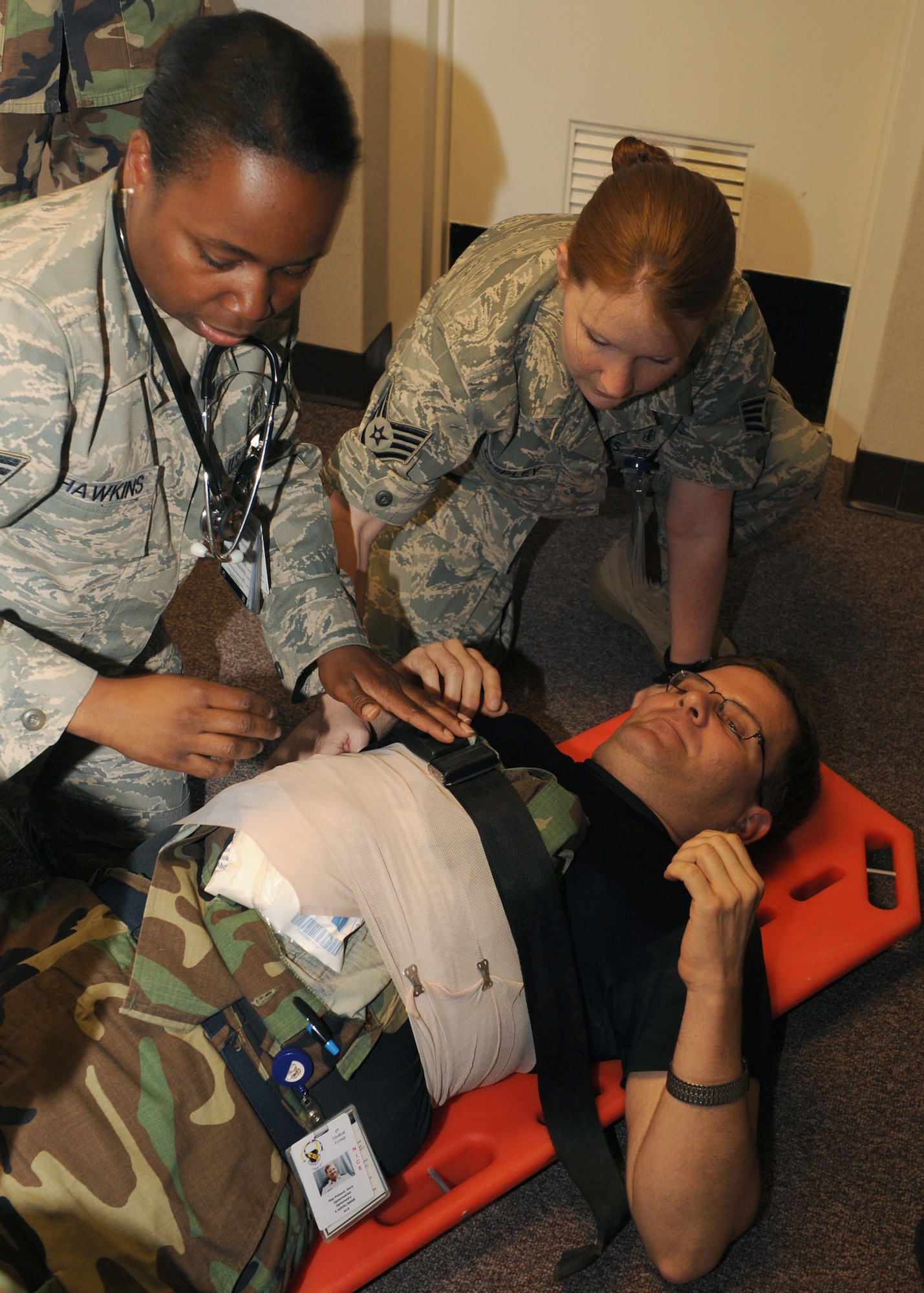 Technical Sergeant Patrenia Hawkins and Staff Sergeant Sarah Chipley practice self aid and buddy care on Major Gary Roland, all from the 4th Medical Group. They are part of a major accident response excercise held to keep them ready in the case of a real life emergency. 