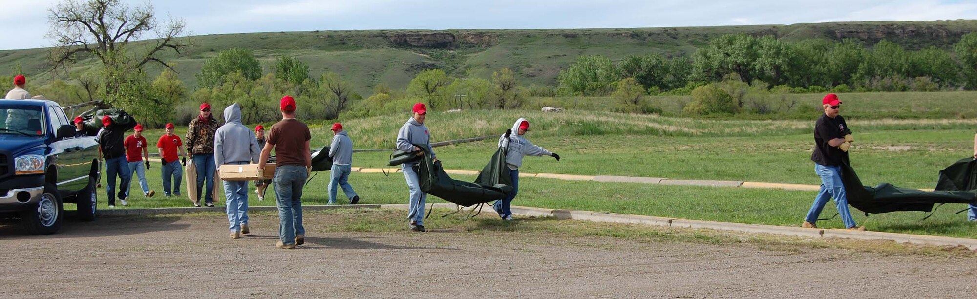 Members of the 819th RED HORSE Squadron unload the tent supplies from the back of a truck June 6. About 30 members of the organization worked together to erect two tents that would be used to support the Montana Fish, Wildlife and Parks annual kid's fishing day at Wadsworth Pond June 7. (U.S. Air Force photo/Valerie Mullett)