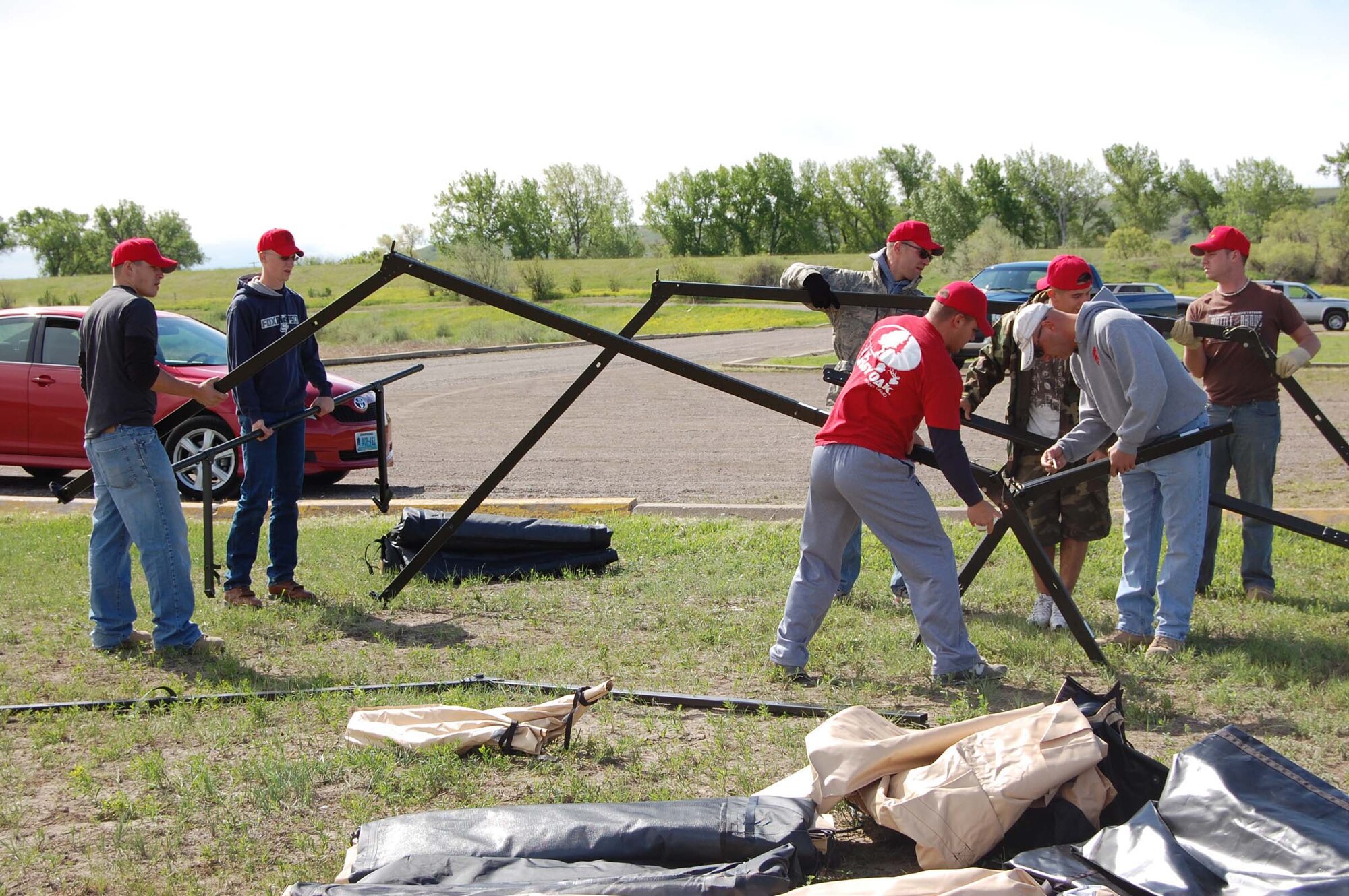 Members of the 819th RED HORSE Squadron work as a team to construct the framework of a four-panel tent at Wadsworth Pond June 6. The tents were used to house instructional stations during the annual Montana Fish, Wildlife and Parks kid's fishing day at Wadsworth Pond June 7. Children who completed the instruction on various fish species and other related fishing information received a free fishing pole. (U.S. Air Force photo/Valerie Mullett)