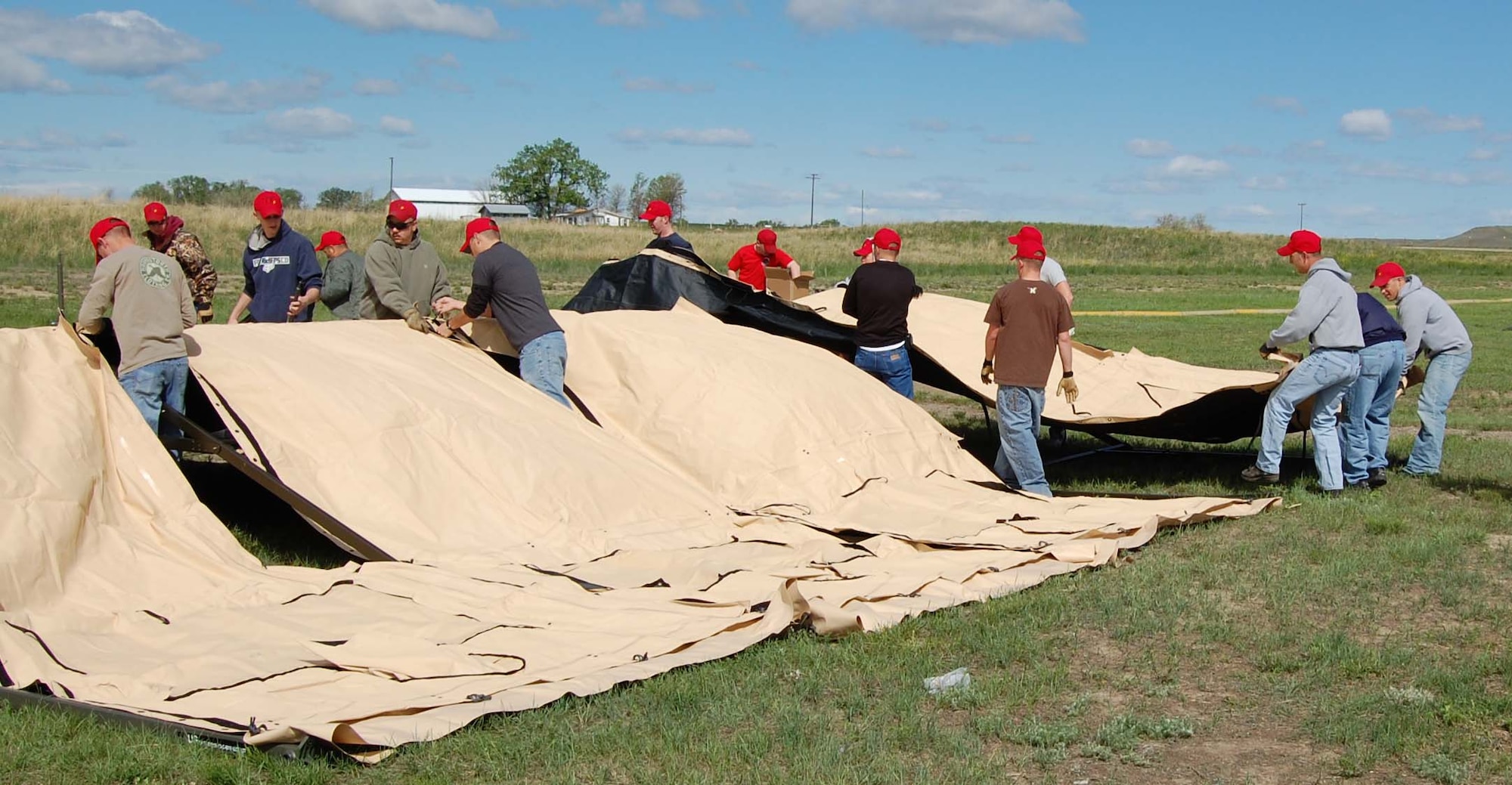 Members of the 819th RED HORSE Squadron work together to position the canvas flaps over the four-panel tent frame June 6. The group donated their time and resources to support the annual Montana Fish, Wildlife and Parks-sponsored kid's fishing day at Wadsworth Pond. (U.S. Air Force photo/Valerie Mullett)