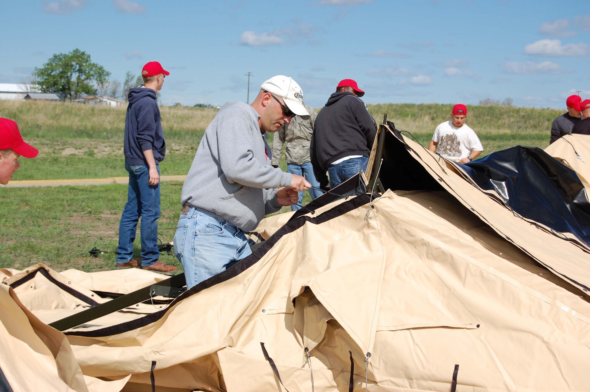 Staff Sgt. Ken Weir fastens the ties to secure the canvas flaps to the tent frame. About 30 members of the 819th RED HORSE Squadron set up two tents at Wadsworth Pond June 6 to support the annual kid's fishing derby sponsored by Montana Fish, Wildlife and Parks. (U.S. Air Force photo/Valerie Mullett)