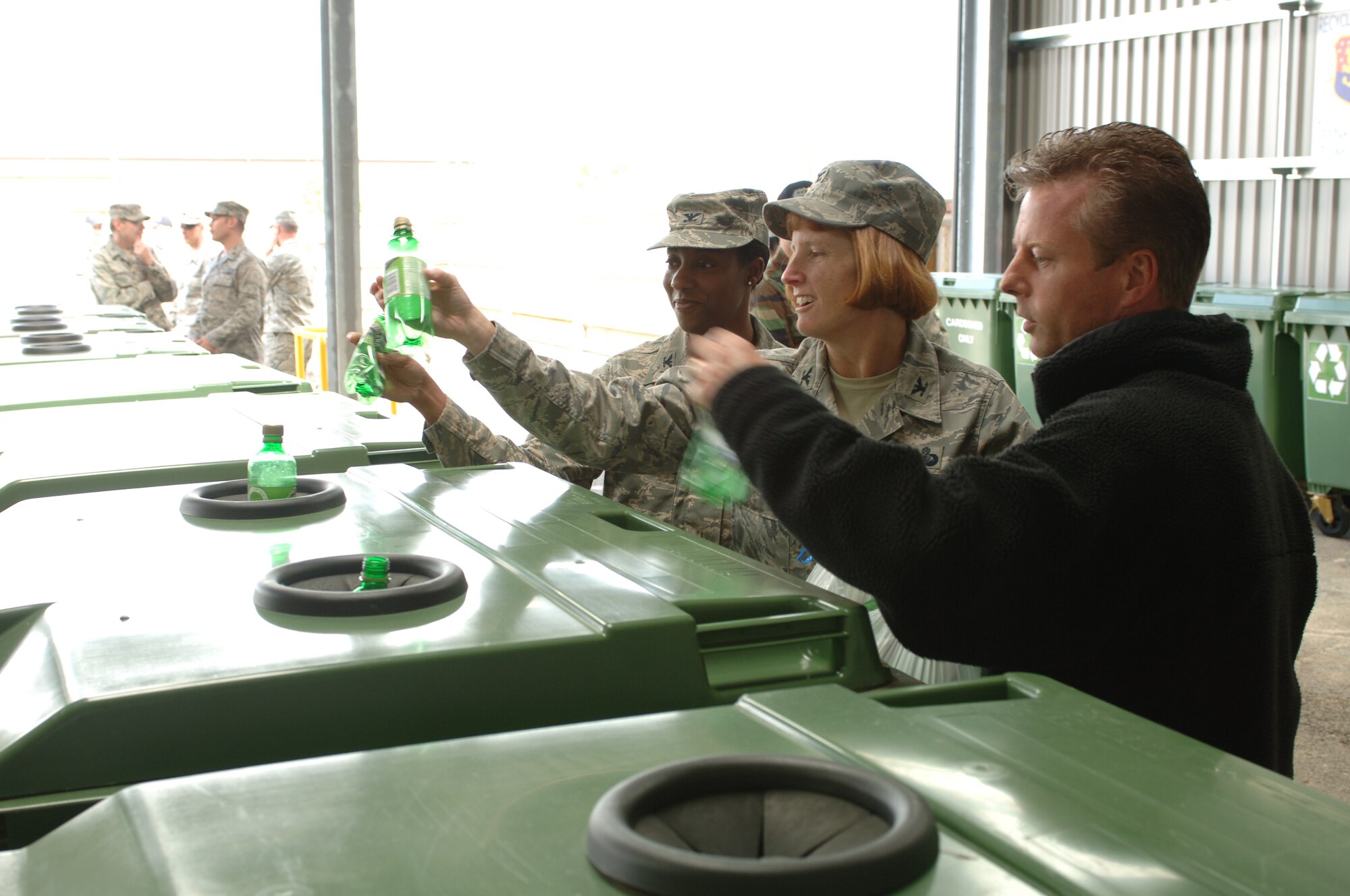 Col. Kimberly Toney (center), 501st Combat Support Wing Commander, Col. Sharon Holmes, 422nd Air Base Group Commander, and Mr. Alex Wilkieson, 422nd Civil Engineering Squadron Environmental Flight Chief deposit the first recyclable material into the new RAF Croughton recycling facility following the ribbon cutting ceremony June 12. The new weather-protected facility has areas for just about every type of recylable material as well as a re-useable material area.