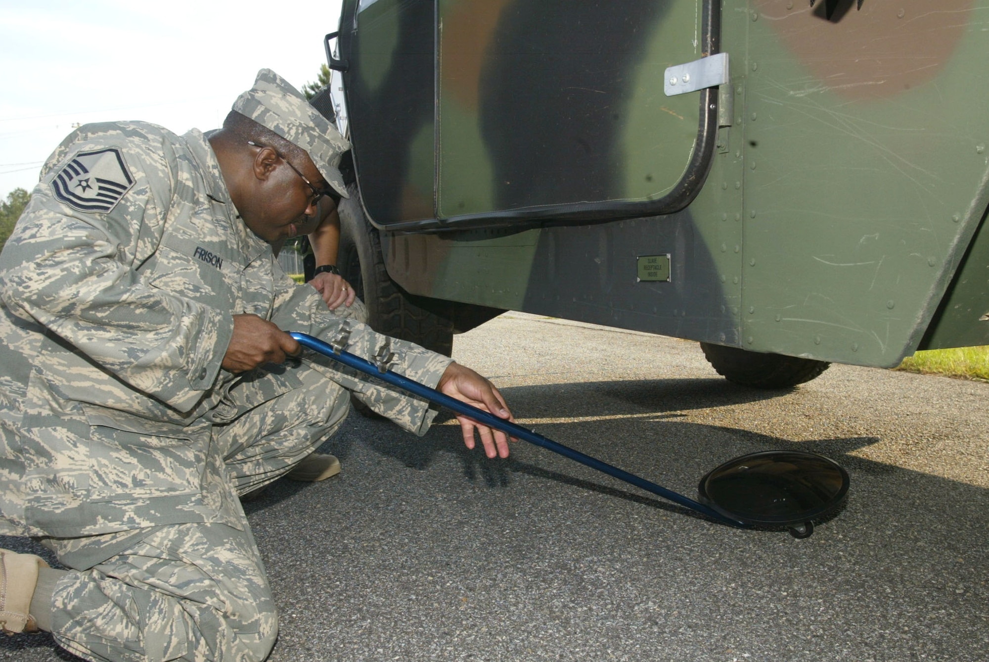 DOBBINS AIR RESERVE BASE, Ga. -- Master Sgt. Jesse Frison from the 94th Security Forces Squadron uses a mirror to search for explosive training devices hidden on a HUMVEE.  The training devices were placed in various locations on the vehicle by 94th Civil Engineer Squadron Explosive Ordnance Disposal personnel to help train security forces members on explosives search procedures. (Air Force photo/Don Peek)
