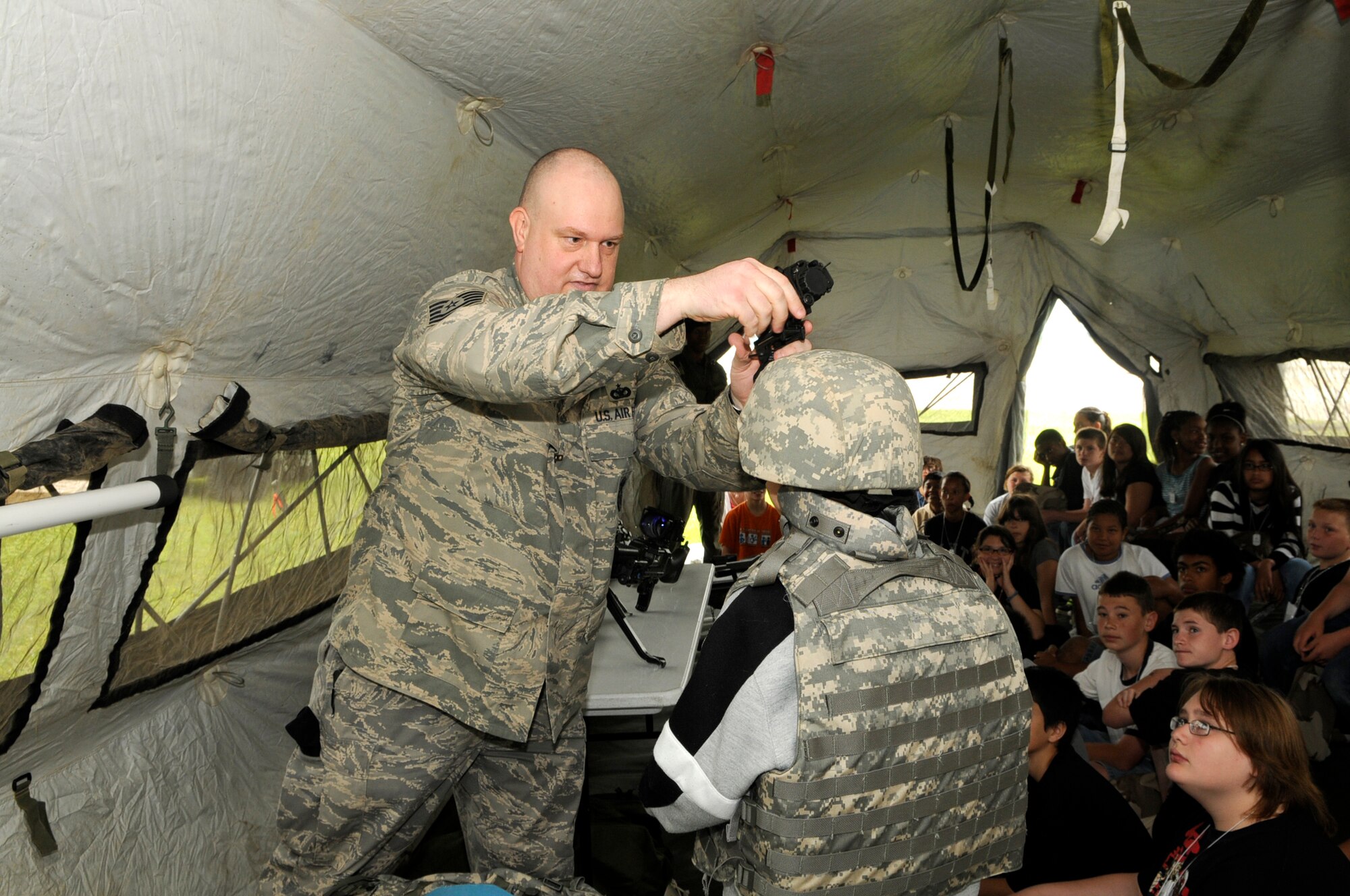 Tech. Sgt. John Knipe from the 305th Security Forces Squadron adjusts the night vision goggles for Christian Bangs, a sixth grade student from Upper Elementary School in North Hanover. Bangs was part of a field trip to McGuire to participate in a deployment mobility line. The students took part in a mobility line that culminated with their simulated trip to Saudi Arabia. The field trip gave the sixth grade students a perspective of the troops that deploy for contingencies. U.S. Air Force photo/Kenn Mann