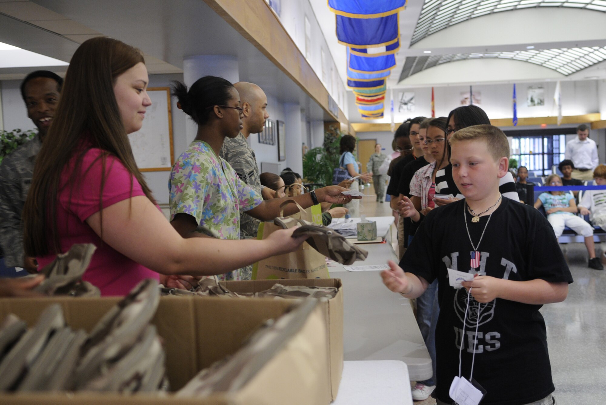 Veronica Bass, a military spouse volunteer, hands out mobility bags during a deployment line for students from Upper Elementary School in North Hanover. The students took part in a mobility line that culminated with their simulated trip to Saudi Arabia. The field trip gave the sixth grade students a perspective of the troops that deploy for contingencies. (U.S. Air Force photo/Kenn Mann)