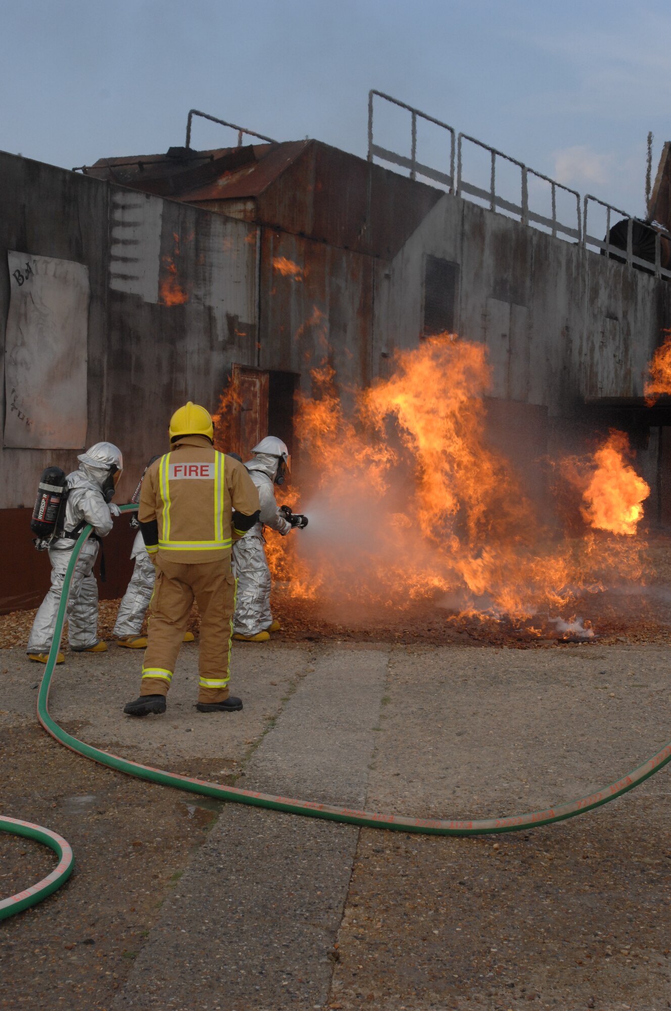 Firefighters from RAF Mildenhall, RAF Lakenheath, and Lajes Field battle a simulated  aircraft fire at the USAFE regional fire trainer as the safety monitor looks on.  (U.S. Air Force Photo By Senior Airman Heather K. Stidham)