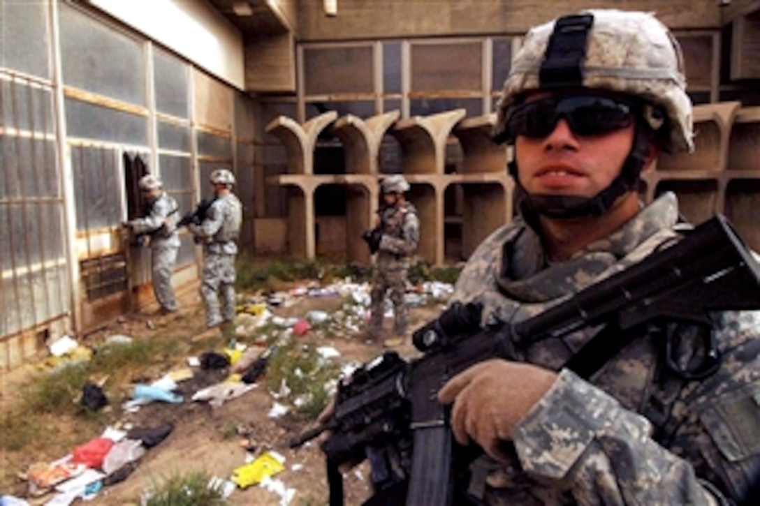 A  U.S. Army soldier stands guard while fellow soldiers attempt to enter a building that will be undergoing renovation in Mahmudiyah, Iraq, June 9, 2008. The soldiers are assigned to the 101st Airborne Division's 320th Field Artillery Regiment, 3rd Brigade Combat Team. 
