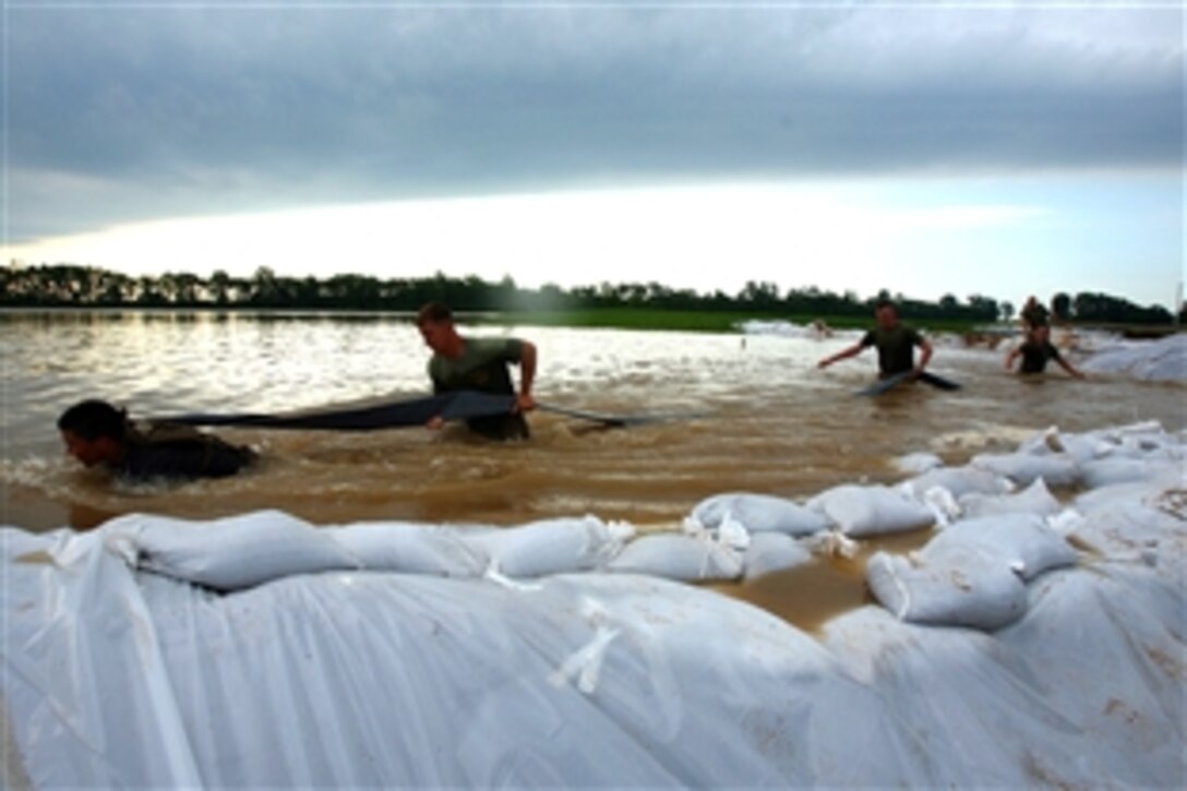 Marines and sailors of Battalion Landing Team 2/6, 26th Marine Expeditionary Unit move a hose through the water from the White River June 9, 2008, in Elnora, Ind.  Local authorities in Elnora requested the 26th MEU to provide support to reinforce the levees from flooding of the White River. 