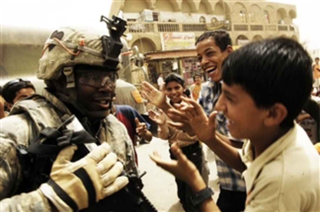 U.S. Army Sgt. David Williams from the 2nd Brigade Combat Team, 502nd Infantry Regiment dances while Iraqi children sing and clap in Shula, Iraq, on June 8, 2008.  Williams and his unit installed concrete barriers throughout the city.  