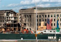 The American Flag, draped over the wall of the Pentagon by firemen and military personnel on the day after the Sept. 11th terrorist attack, is lowered on Oct. 11, 2001. The ceremonial lowering, exactly one month after the terrorist attack was performed by a team of U.S. Army soldiers from the Military District of Washington. Defense Department photo by R. D. Ward.