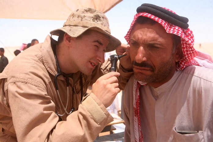 Navy Lt. Michael W. Pruitt, a surgeon with 2nd Light Armored Reconnaissance Battalion, Regimental Combat Team 5, inspects the ear of Razzi Abbu Ali, 35, a resident of Nathara, Iraq, during a medical support operation for the people in the village June 12. Pruitt, 32, from Jacksonville, N.C., was one of many medical specialists to participate in the mission to provide the residents water, medical diagnosis and treatment.