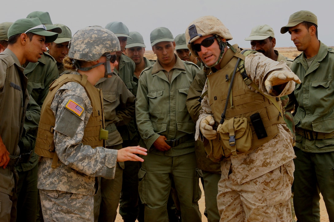Capt. Andrew D. Bedo, platoon commander for Weapons Company, 1st Battalion, 23rd Marine Regiment, explains the down range area for live-fire exercises while Spec. Katherine M. Blazzard, a translator with the Utah National Guard, interprets for the Moroccan military. The Marines took part in a weapons demonstration here with the Royal Moroccan Army on June 13, as part of exercise African Lion 08, an annual training exercise promoting unit readiness and enhancing foreign relations.