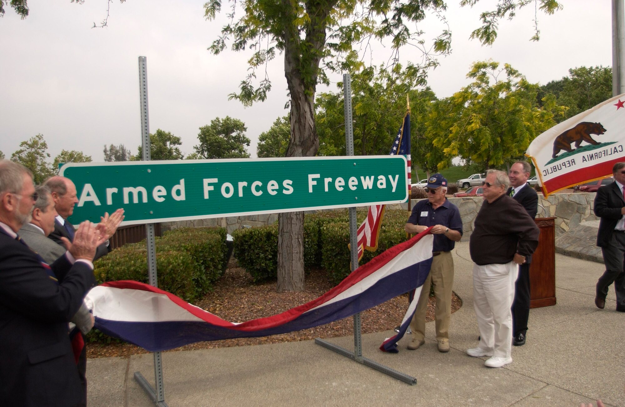 Veterans, March Air Reserve Base representatives and Riverside County officials clap after the unveiling of a road sign bearing the new name of a stretch of I-215 at a dedication ceremony at Riverside National Cemetery, June 4. The 4-mile stretch of road, which runs from Highway 60 (north) to the Ramona Expressway (south), will now be known as “Armed Forces Freeway.” The Caltrans-approved signs, paid for by Riverside supervisors, were installed this week. “These signs will be visible every day to motorists and serve as a reminder of the sacrifice our veterans have given for our country,” said Ken Rolene, Jr., assistant cemetery director.  Col. Jeff Robertson, director of staff, Fourth Air Force, said,”This highway is a tribute to all our colleagues who lie here and whose sacrifice gave us our freedoms.”  (U.S. Air Force photo by Maj. Andra Higgs)