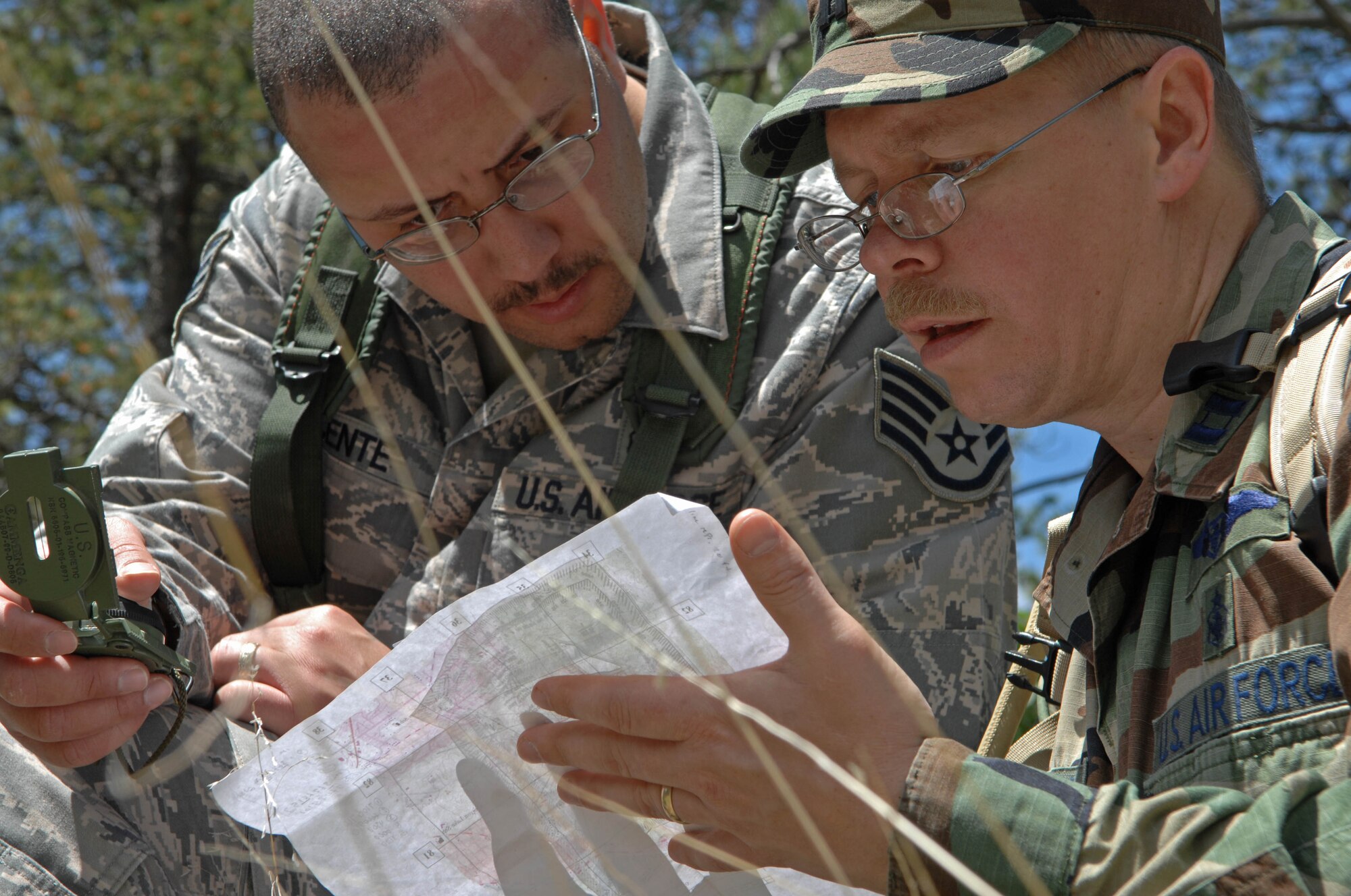 (Right) Capt. Phil Broberg, 28th Medical Operations Squadron education and training chief, and Staff Sgt. Ivan Vicente, ambulance services medical technician, calculate distance and direction to predetermined points of latitude and longitude throughout Camp Rapid, S.D., June 10, 2008. Each team prepares, analyzes and accesses their learned knowledge of geographical surroundings to complete the land navigation exercise. (U.S. Air Force photo/Airman Corey Hook)

