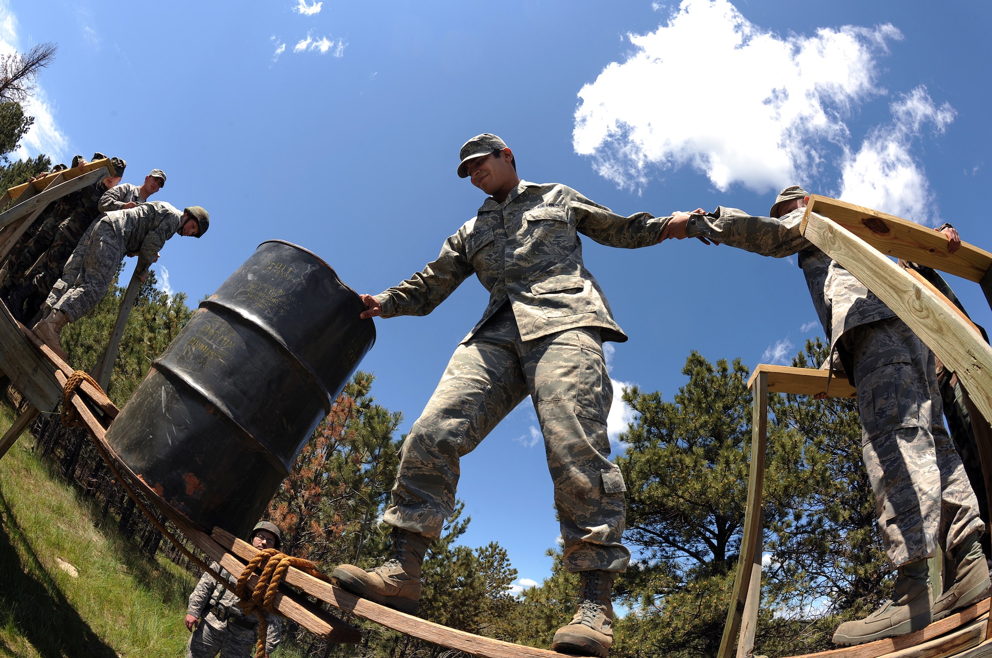As part of The Golden Coyote training exercise, Airman 1st Class Phillip Baiao, Ellsworth Air Force Base 28th Medical Group health services manager, moves a barrel across an improvised bridge on a leadership reaction course obstacle at Camp Rapid, Rapid City, S.D., June 9, 2008. Golden Coyote tests the ability of engineering and support units to mobilize equipment, deploy to a battle zone, coordinate combat and service support missions and re-deploy back to home station. (U.S. Air Force photo/Senior Airman Marc I. Lane)