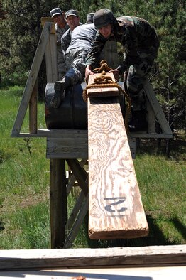As part of the Golden Coyote training exercise, members of the Ellsworth Air Force Base 28th Medical Group create a bridge on a leadership reaction course obstacle at Camp Rapid, Rapid City, S.D., June 9. Golden Coyote tests the ability of engineering and support units to mobilize equipment, deploy to a battle zone, coordinate combat and service support missions and re-deploy back to home station. (U.S. Air Force photo/Senior Airman Marc I. Lane) 
