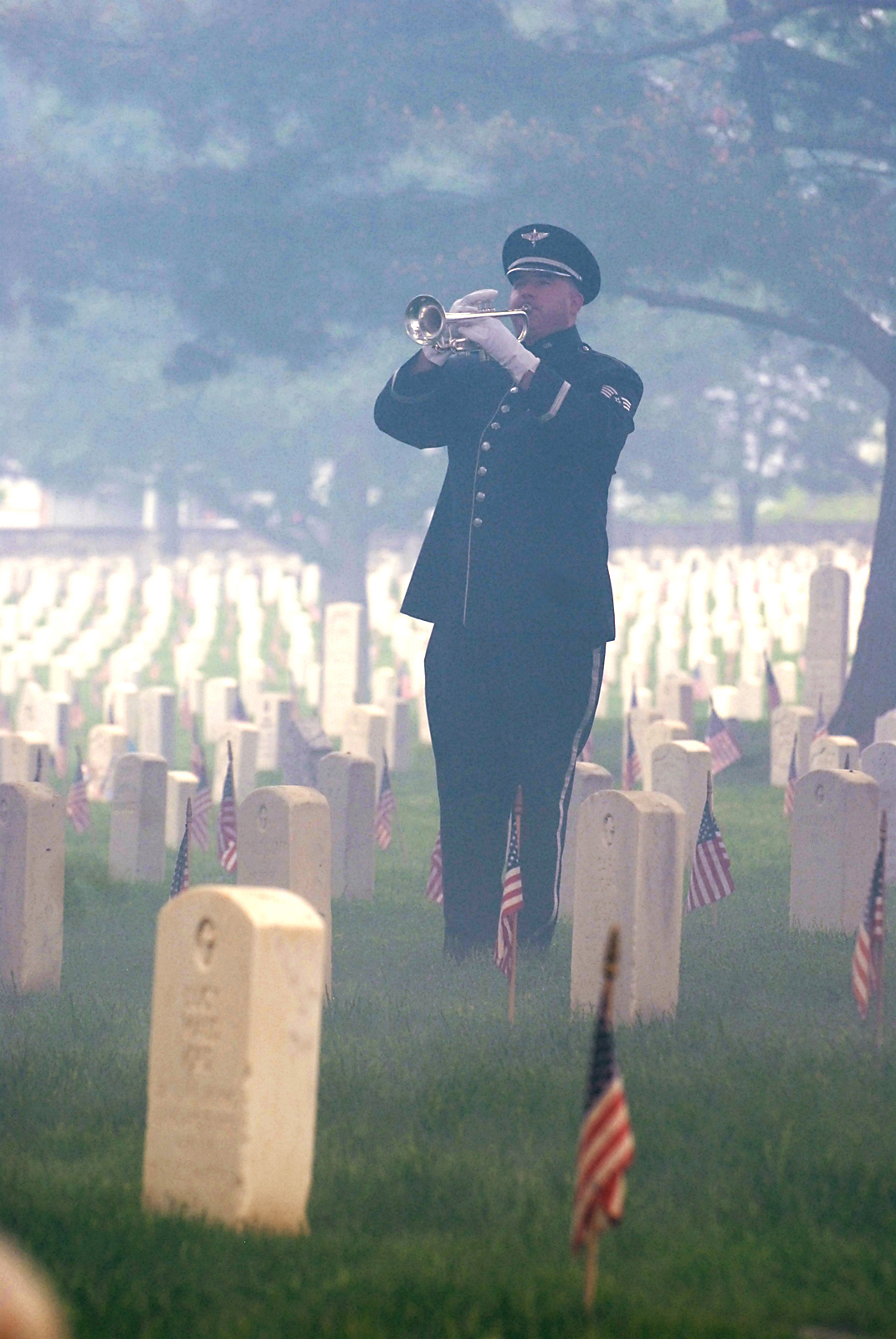 Through the smoke from the National Salute, Staff Sgt. Eric Proper of the USAF Heartland of America Band's Brass in Blue flawlessly performs a heartfelt rendition of "Taps."  This performance was part of a Memorial Day Ceremony at Fort Leavenworth National Cemetery in Kansas.  (Photo by Prudence Siebert/Fort Leavenworth Lamp)