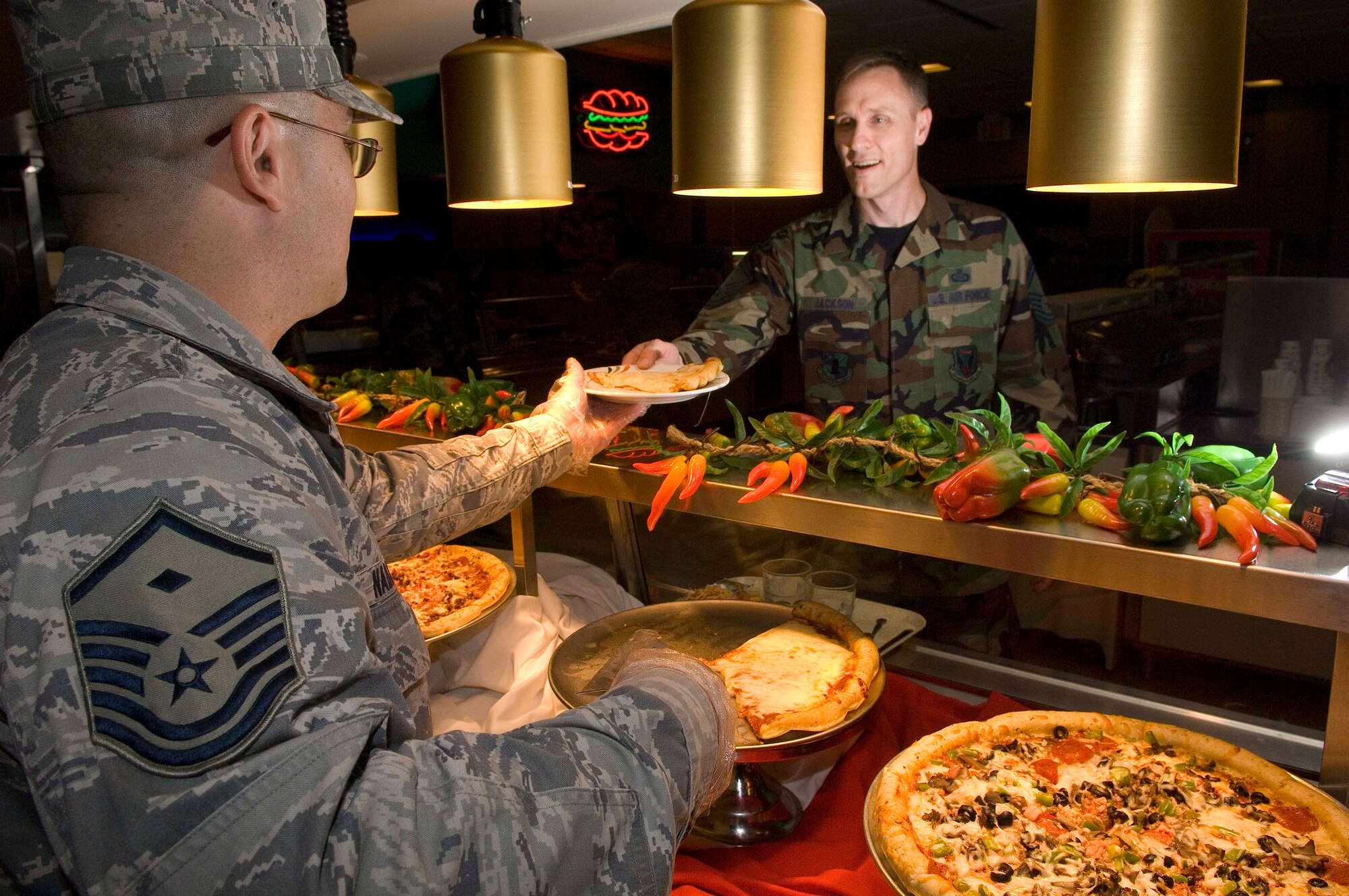 LANGLEY AIR FORCE BASE, Va. -- Master Sgt. Kraig Nadjkovic, 83rd Network Operations Squadron first sergeant, serves pizza to Senior Master Sgt. Kevin Jackson, 480th Intelligence Wing operations superintendent, at the Eagle Room Dining Facility here June 12.  Langley first sergeants often volunteer to serve pizza on Thursdays. (U.S. Air Force photo/Senior Airman Barry Loo)