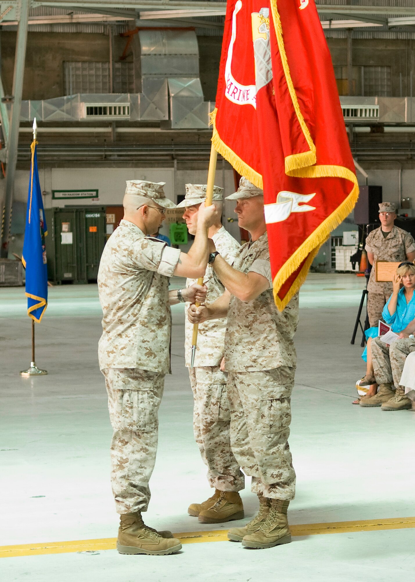 Marine Lt. Col. Christopher Keane (right), the new Marine Aircraft Group 46 Detachment Bravo commanding officer receives the Marine Corps flag from Sgt. Maj. Michael Brookman (left), MAG 46 Det. B sergeant major, as Lt. Col. Thomas McCarthy (center), the unit's former commanding officer, looks on. Colonel Keane took command of MAG 46 Det. B during a change of command ceremony at hangar 1210 here June 12. (Air Force photo by Mike Cassidy)