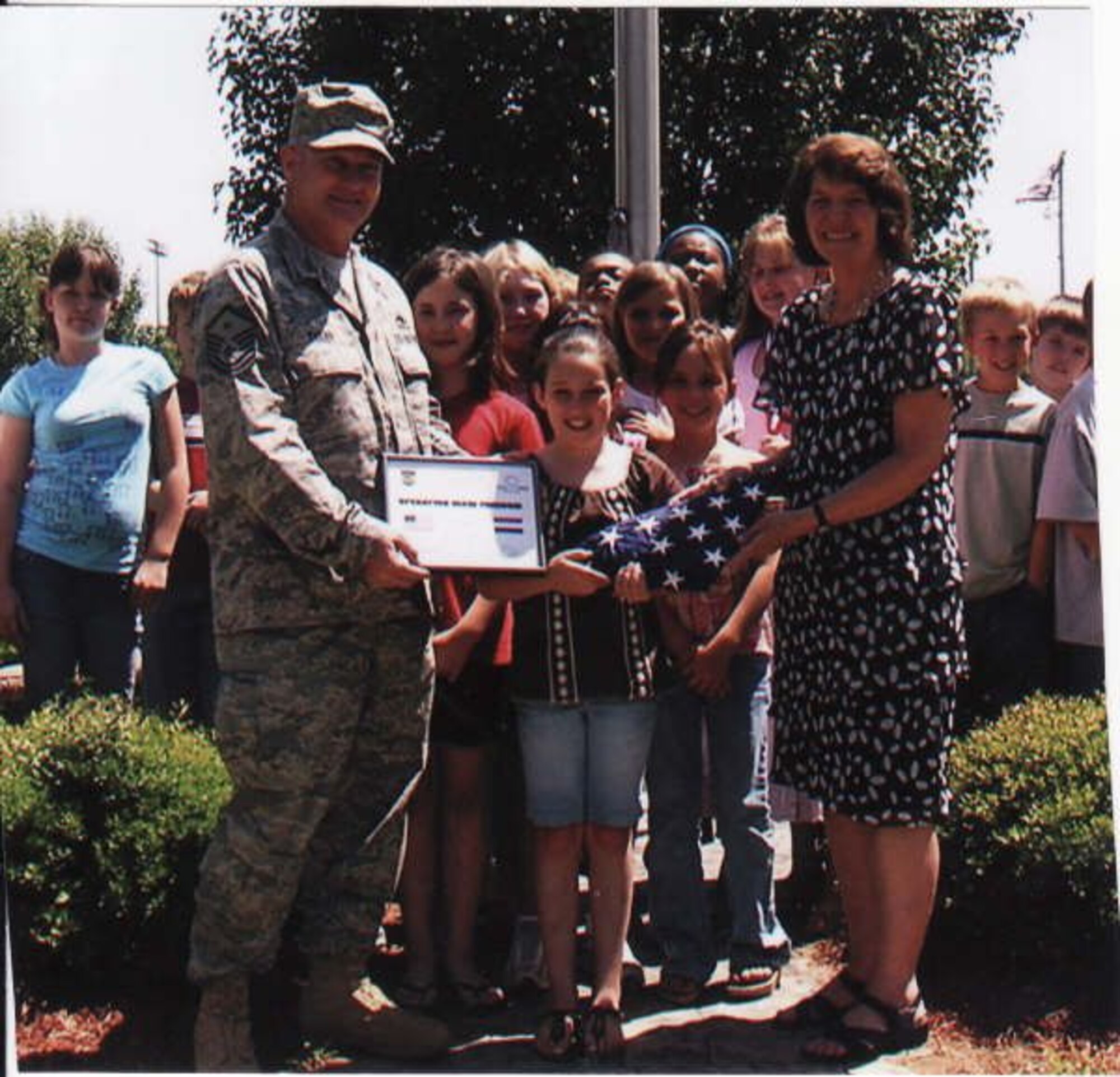 Master Sgt. George Evans, 14th Medical Group First Sergeant, presents a flag he flew over his workplace while deployed to Iraq to his daughter’s fourth grade class and their teacher, Sandra Murphy. The Caledonia Elementary students sent Sergeant Evans letters of support during his tour. (Courtesy Photo)