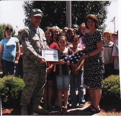 Master Sgt. George Evans, 14th Medical Group First Sergeant, presents a flag he flew over his workplace while deployed to Iraq to his daughter’s fourth grade class and their teacher, Sandra Murphy. The Caledonia Elementary students sent Sergeant Evans letters of support during his tour. (Courtesy Photo)
