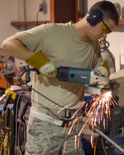 BALAD AIR BASE, Iraq -- Sparks fly as Senior Airman Zach Jones, a structural maintenance welder assigned to the 332nd Expeditionary Aircraft Maintenance Squadron Fabrication Flight, uses a power saw to manipulate a piece of metal here, June 10. The structural maintenance Airmen are responsible for maintaining and repairing anything pertaining to the structure of aircraft, such as wings, panels and hinges. More than 50 active-duty, Reserve and Air National Guard Airmen run the Fabrication Flight shop 24/7 and complete more than 1,400 jobs monthly. Airmen Jones is deployed from the 20th Equipment Maintenance Squadron at Shaw Air Force Base, S.C.  (U.S. Air Force photo /Staff Sgt. John Ayre)